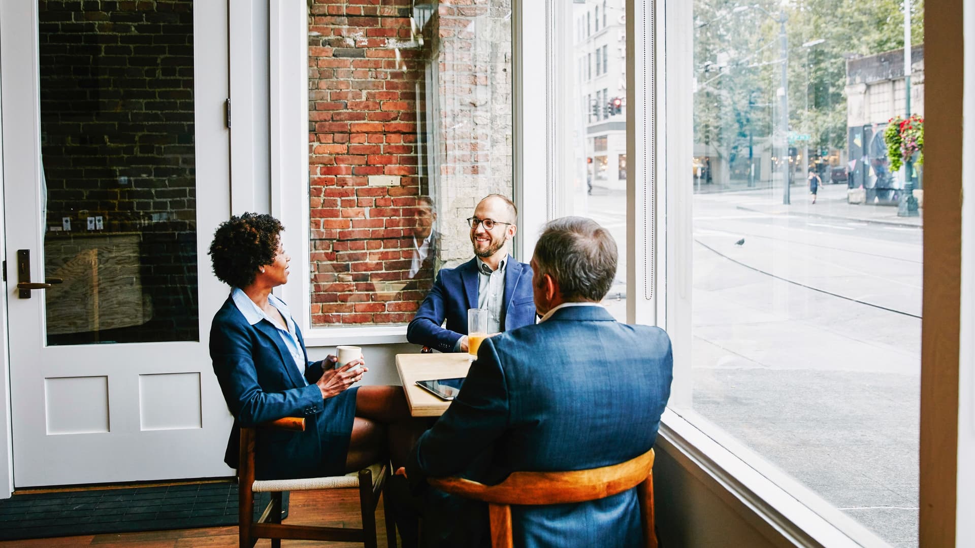Zwei Männer und eine Frau unterhalten sich an einem Tisch.
