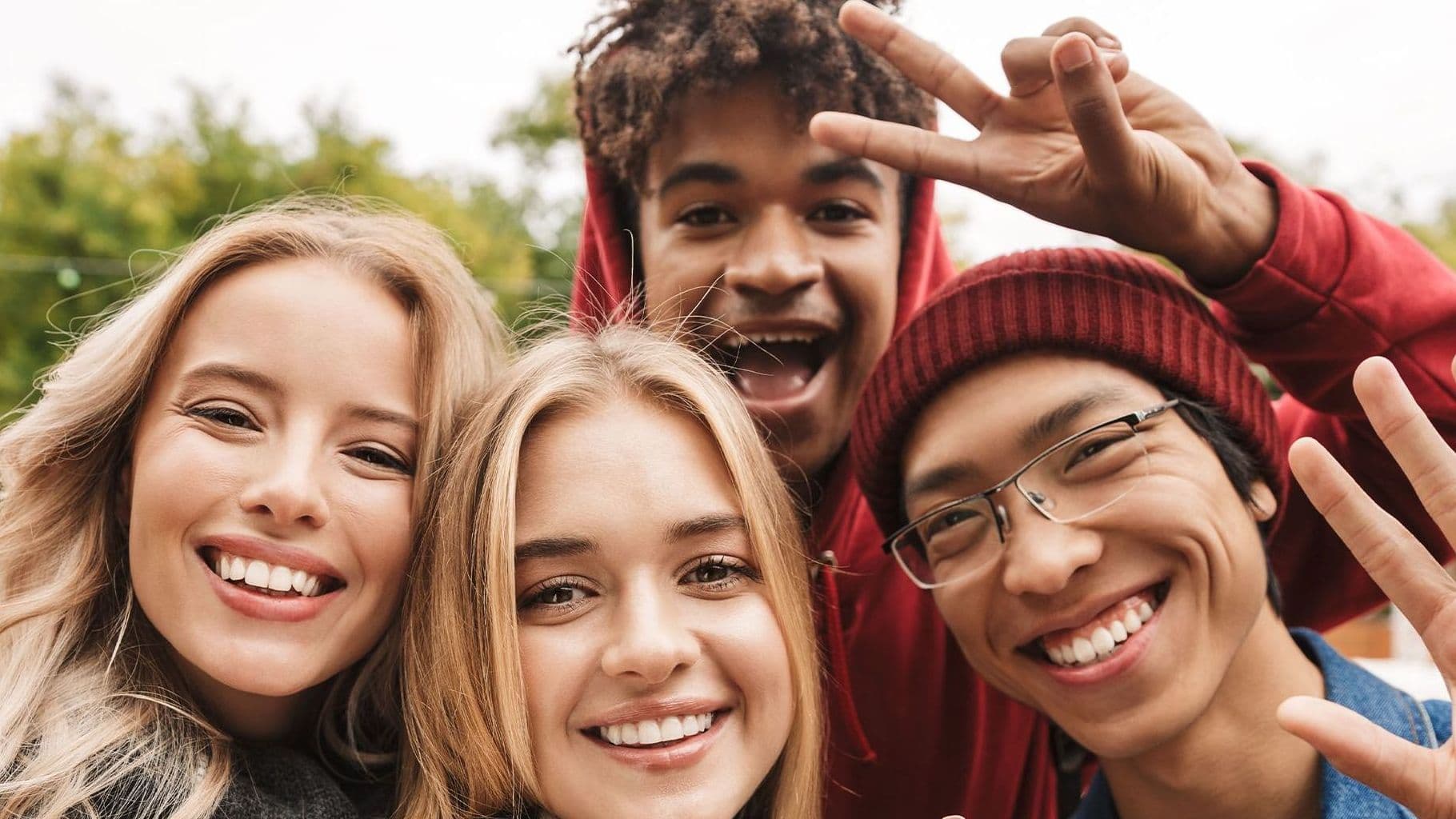 Gruppe junger Menschen lächelt und winkt in die Kamera