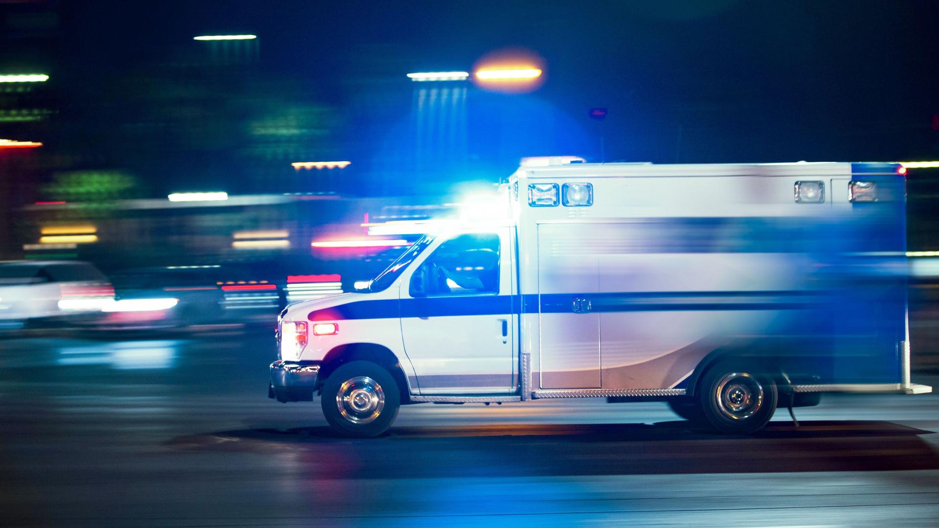 Ein Krankenwagen fährt nachts mit Blaulicht.