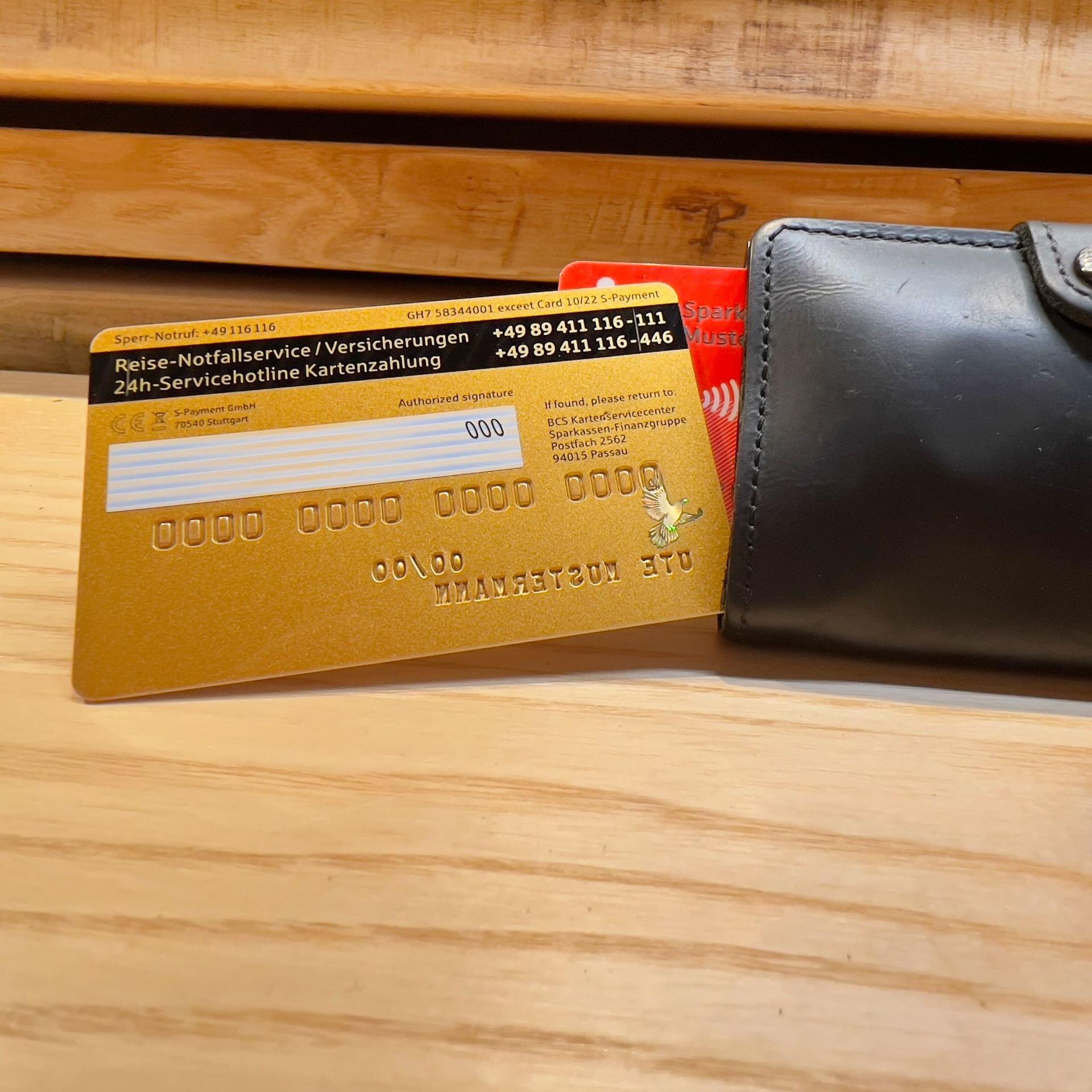 Eine goldene Kreditkarte liegt auf einem Geldbeutel. Die Prüfziffer ist sichtbar.