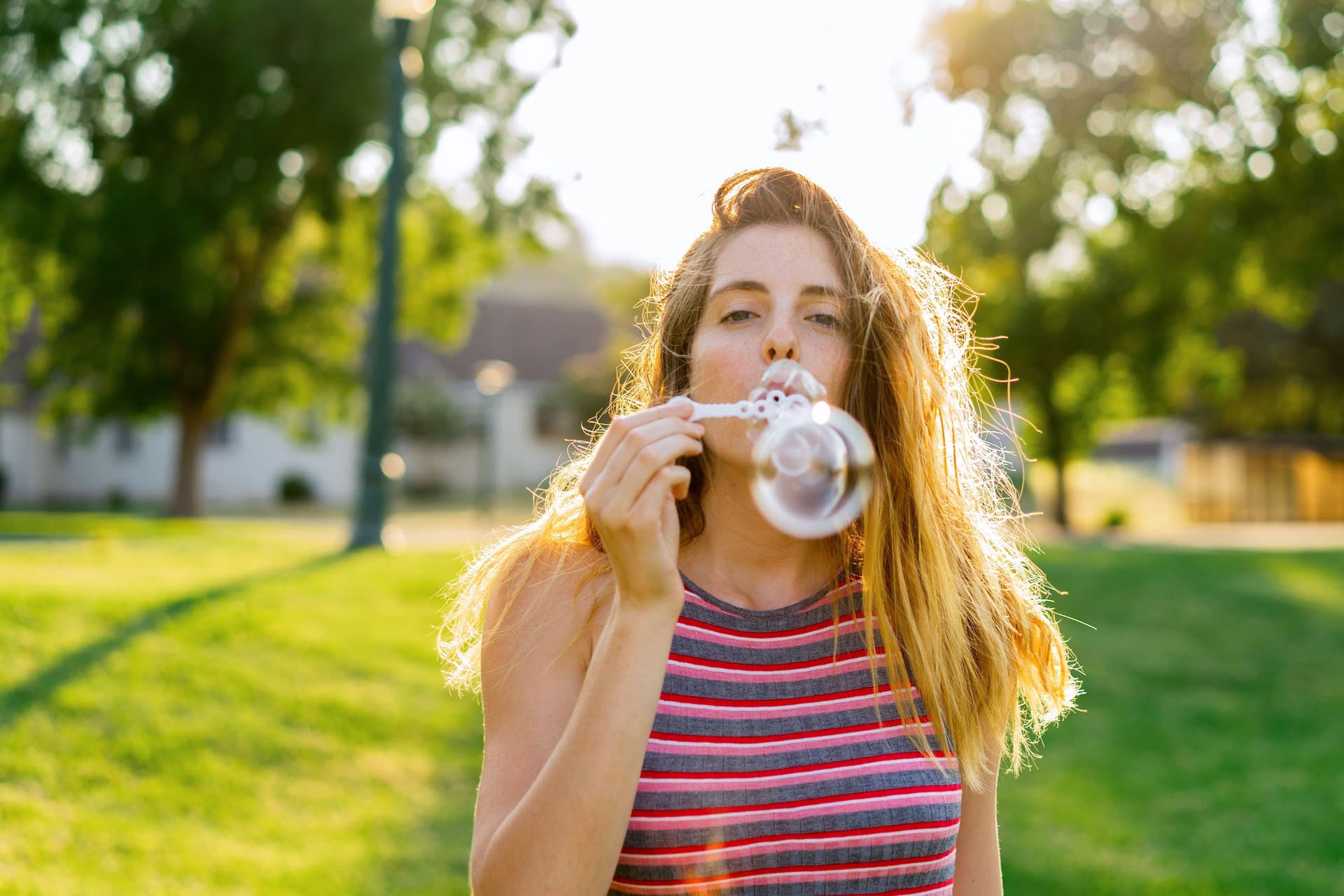 Junge Frau bläst Seifenblasen im Park