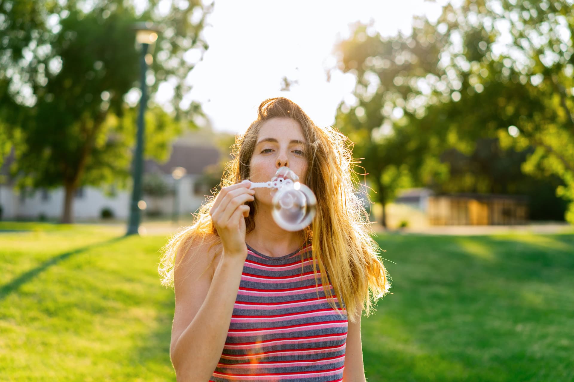 Junge Frau bläst Seifenblasen im Park