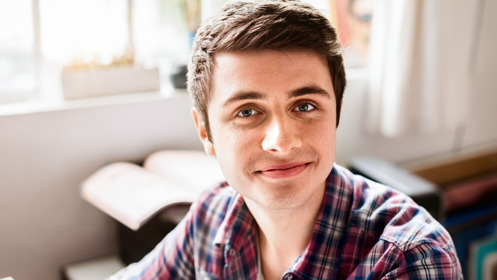 Junger Mann im karierten Hemd blickt in die Kamera