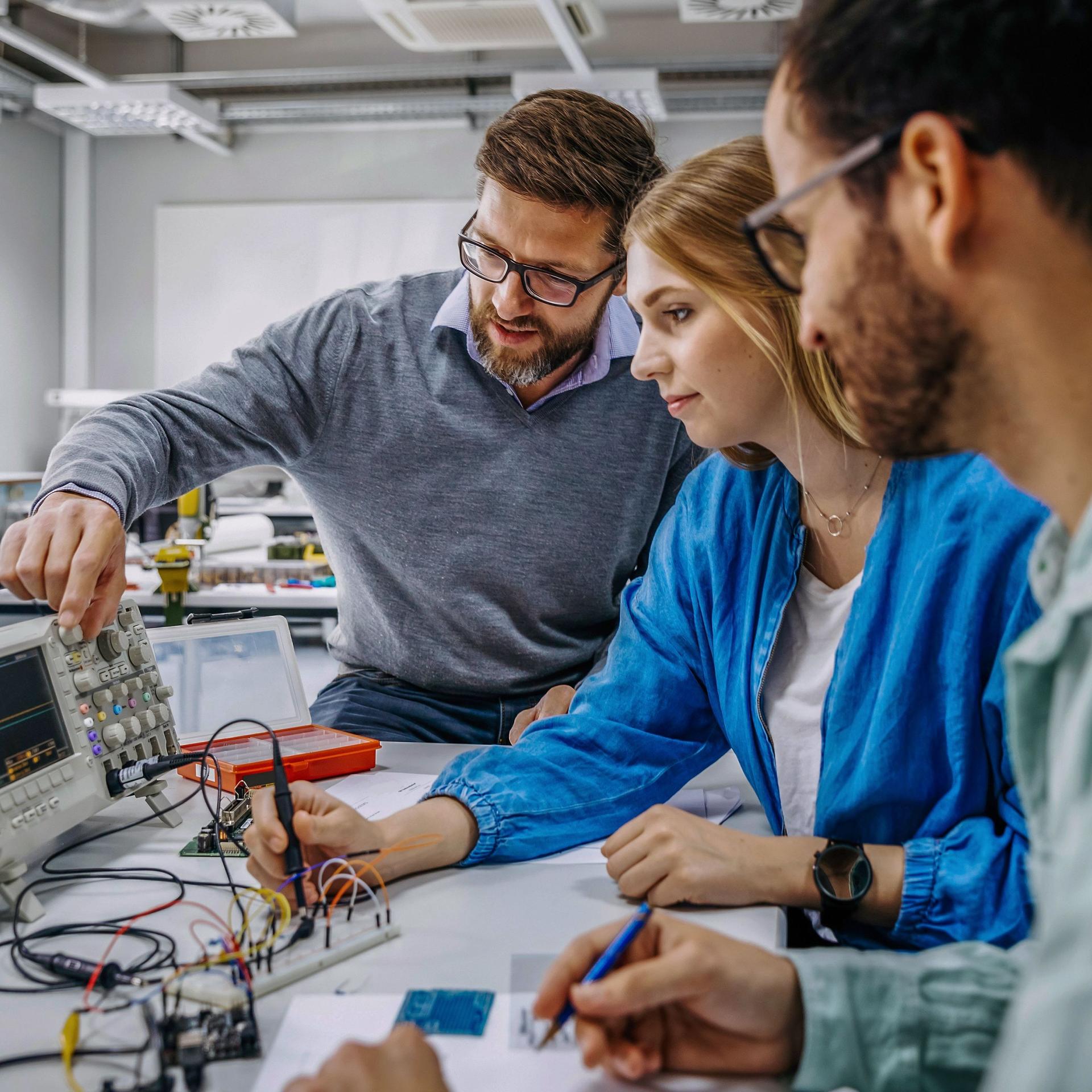 Universitätslehrer instruiert Studenten an elektronischen Geräten