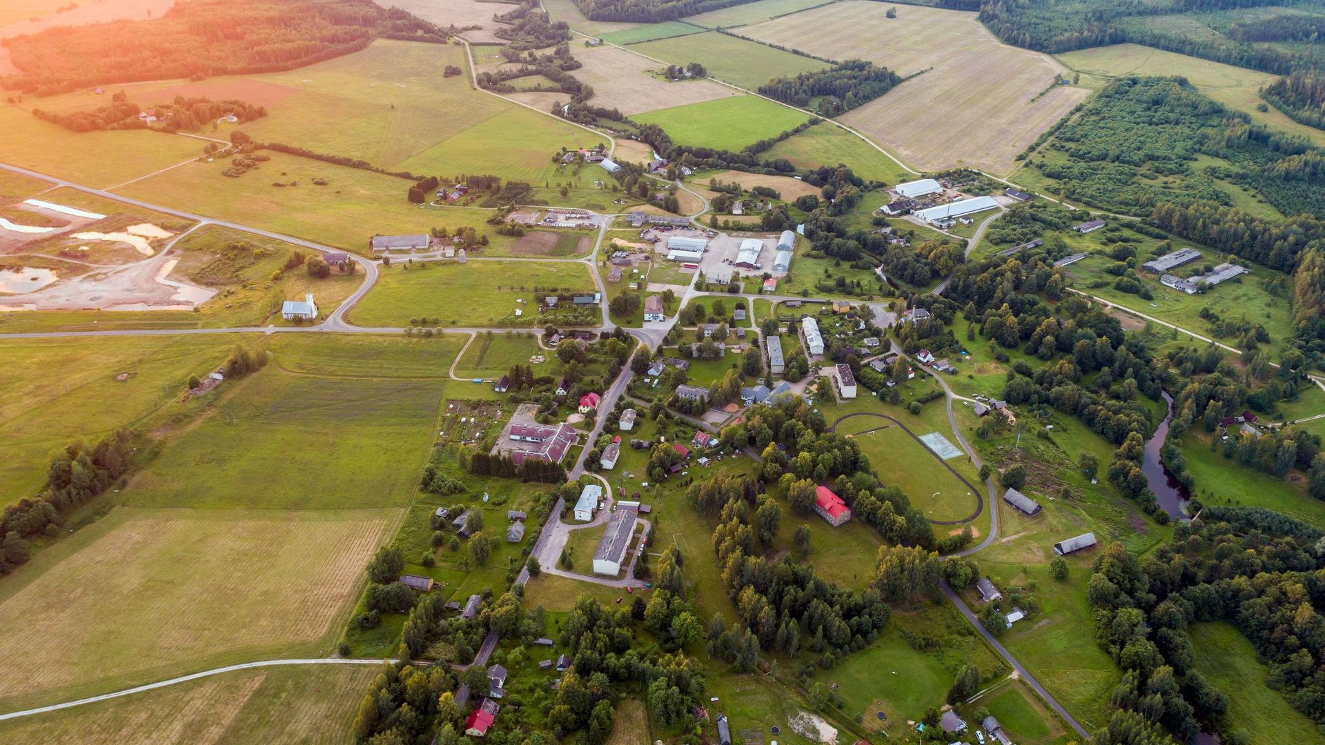 Luftaufnahme einer kleinen Ortschaft umgeben von Feldern und Wald.