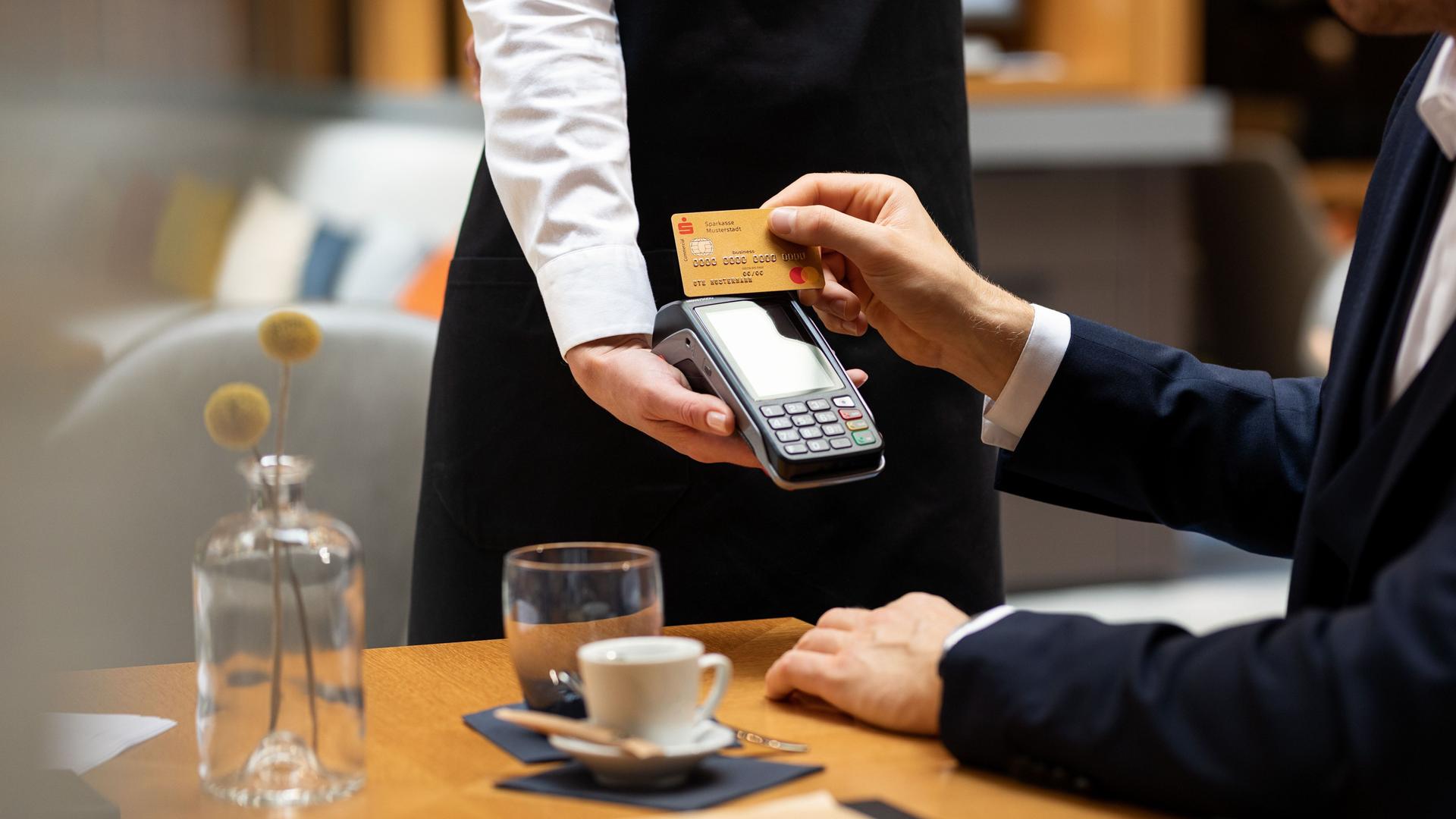 Ein Mann bezahlt in einem Restaurant kontaktlos mit seiner Kreditkarte