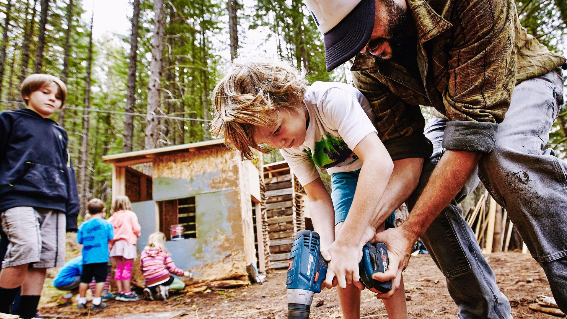 Mann baut Hütte im Wald mit Kinder