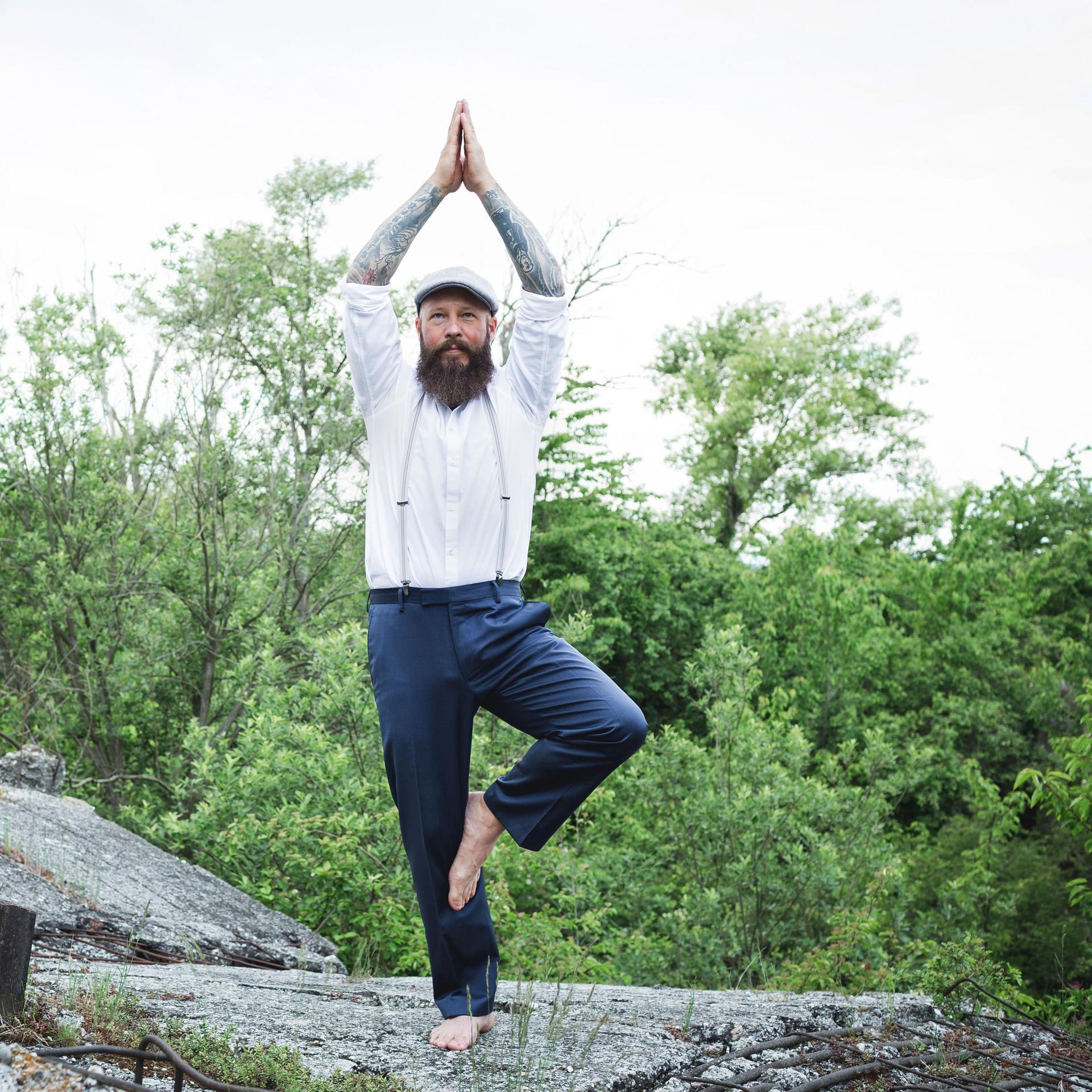 Ein Mann steht auf einem Stein. Er macht Yoga.