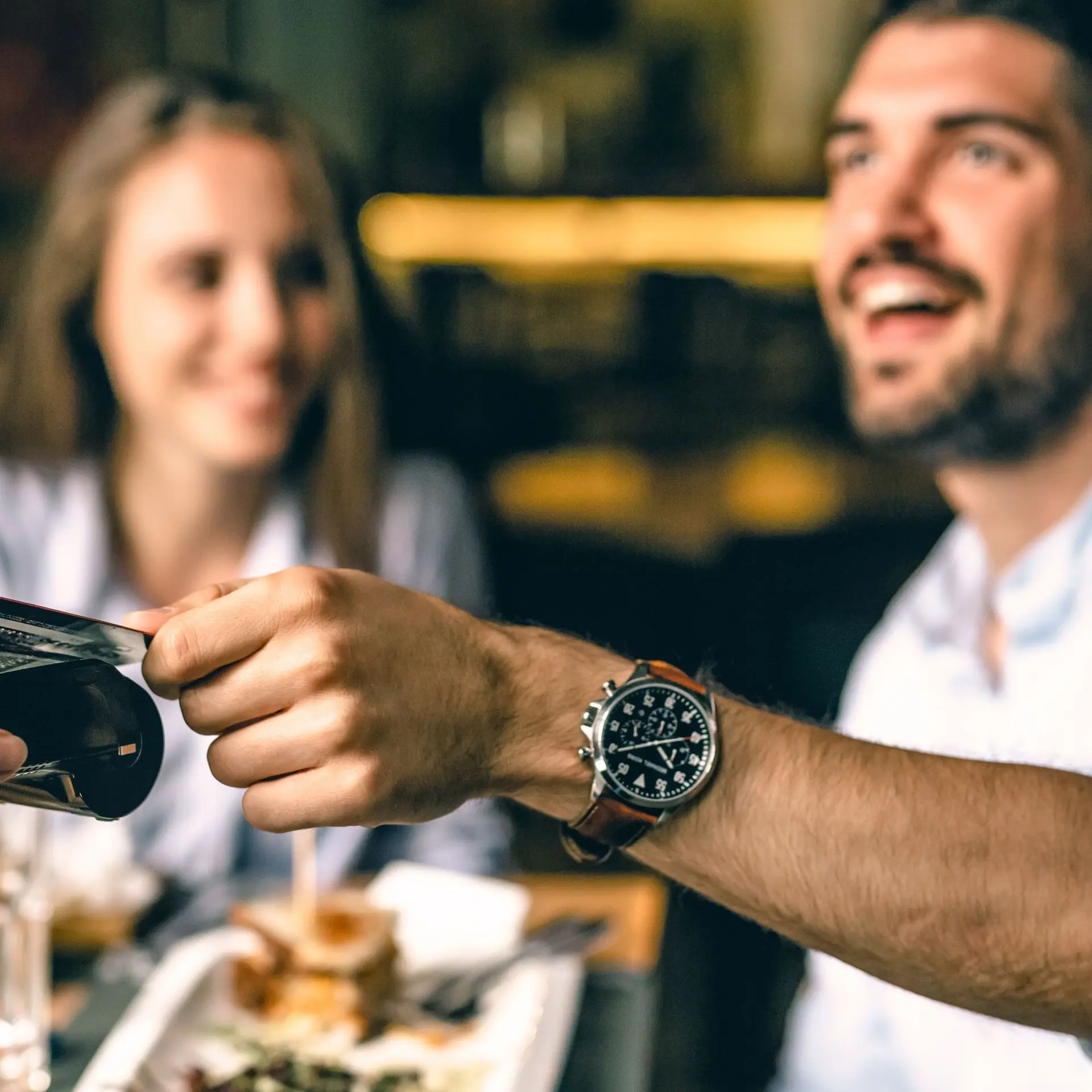 Zufriedener Mann zahlt im Restaurant kontaktlos mit Karte.