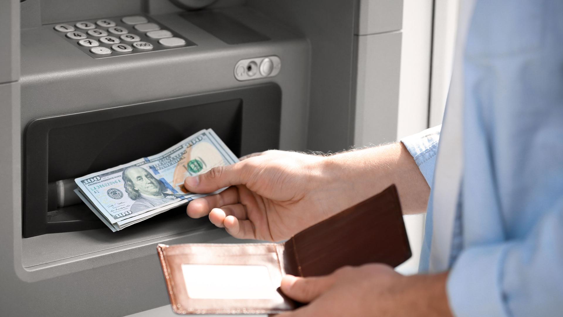 Ein Mann hebt Geld am Bankautomaten ab.