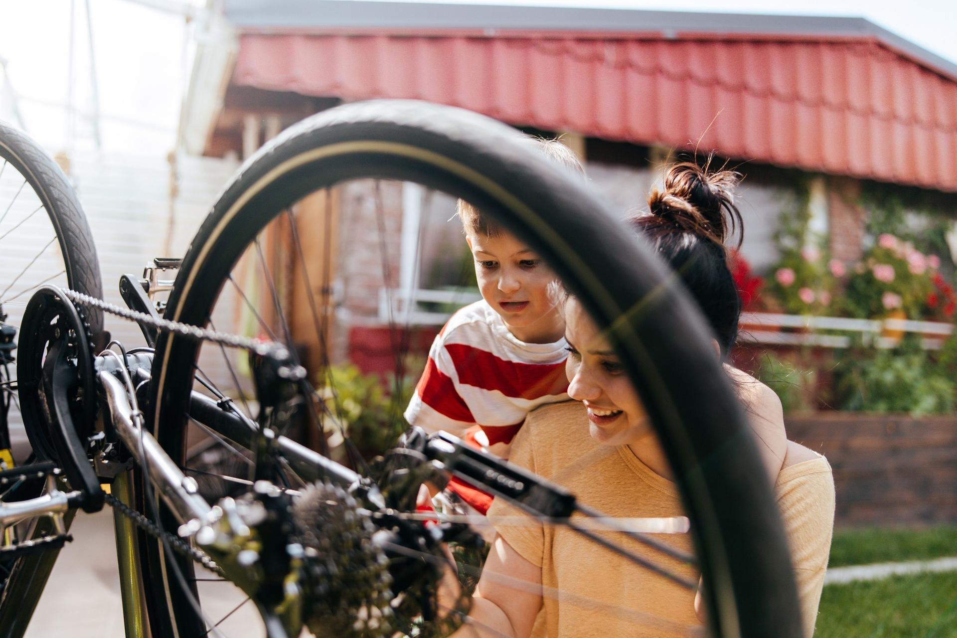 Foto von Mutter und Sohn, die in ihrem Garten ein Fahrrad reparieren.