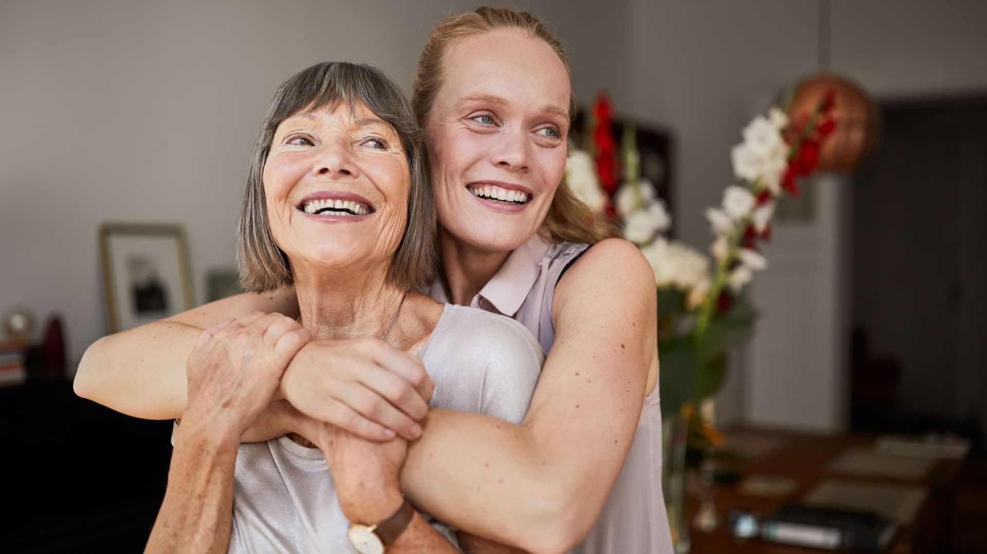 Mutter und Tochter umarmen sich liebevoll in einer Wohnung