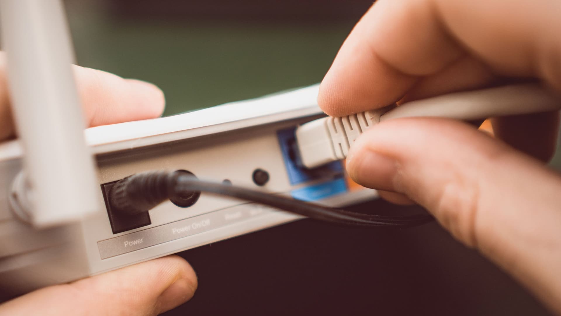 Nahaufnahme einer Person, die ein Internetkabel in einen Router steckt.