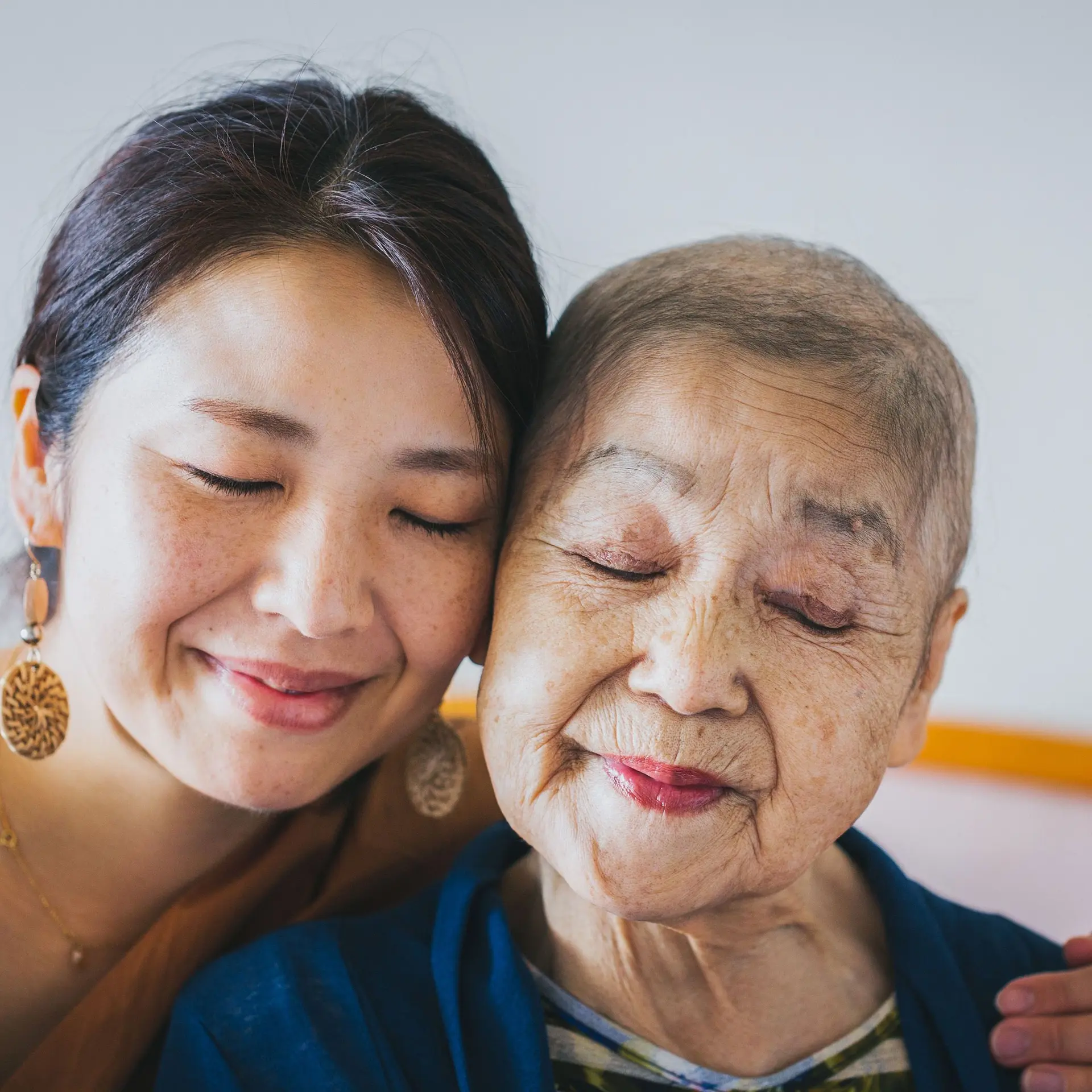 Nahes Portrait einer jungen und einer alten Frau, die sich umarmen