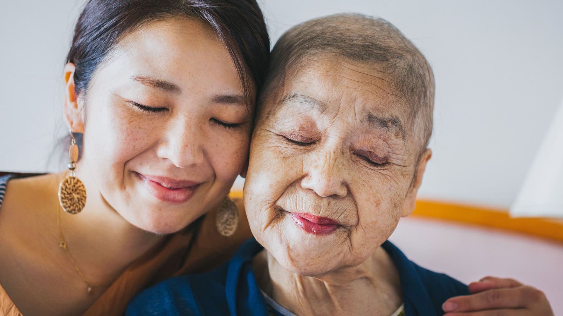 Nahes Portrait einer jungen und einer alten Frau, die sich umarmen