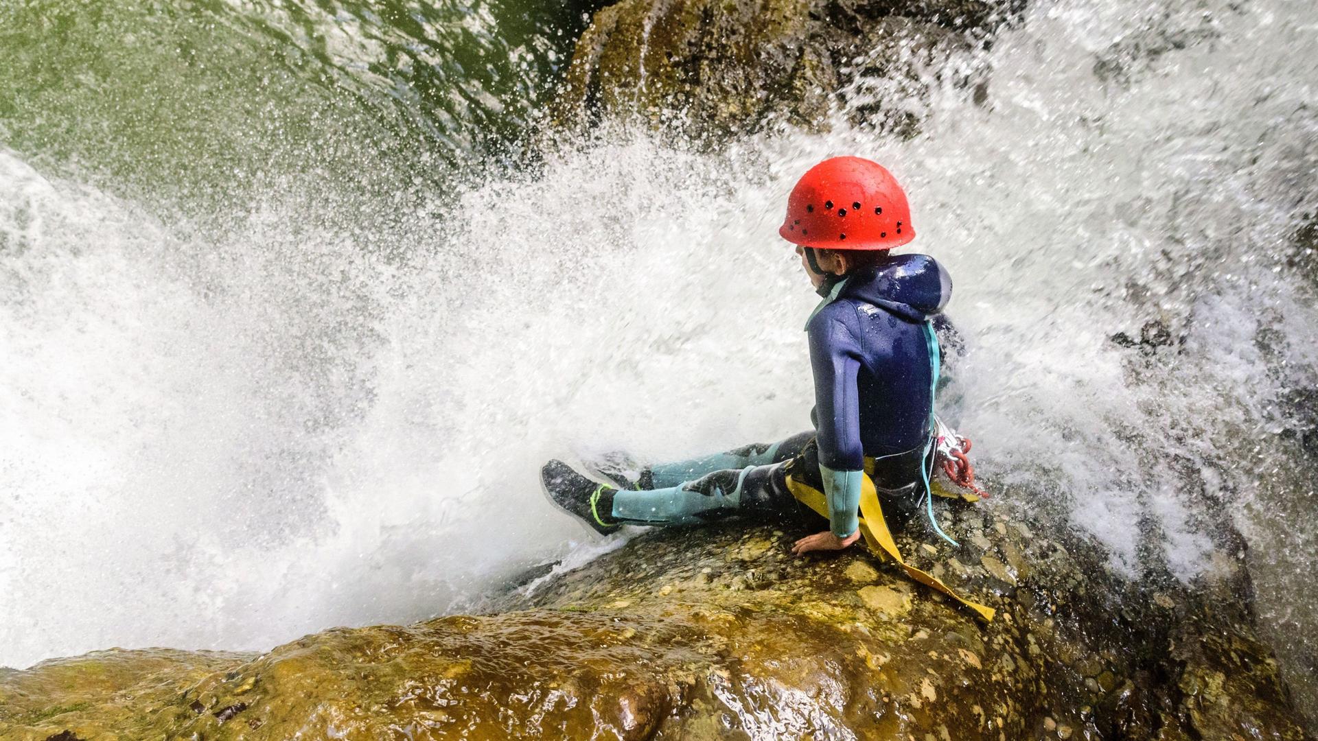 Ein Kind beim Canyoning am Wasserfall.