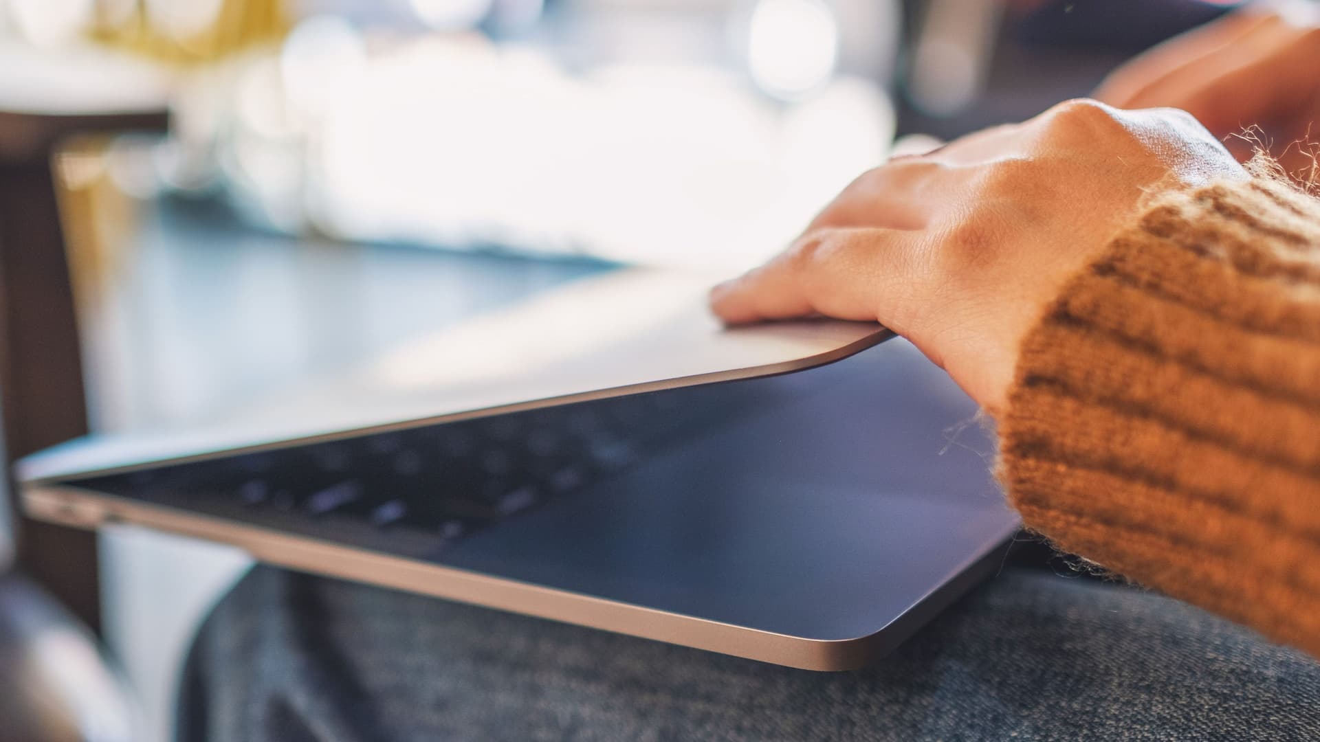 Datensparsamkeit Frau mit Laptop auf den Knien öffnet oder schließt diesen.