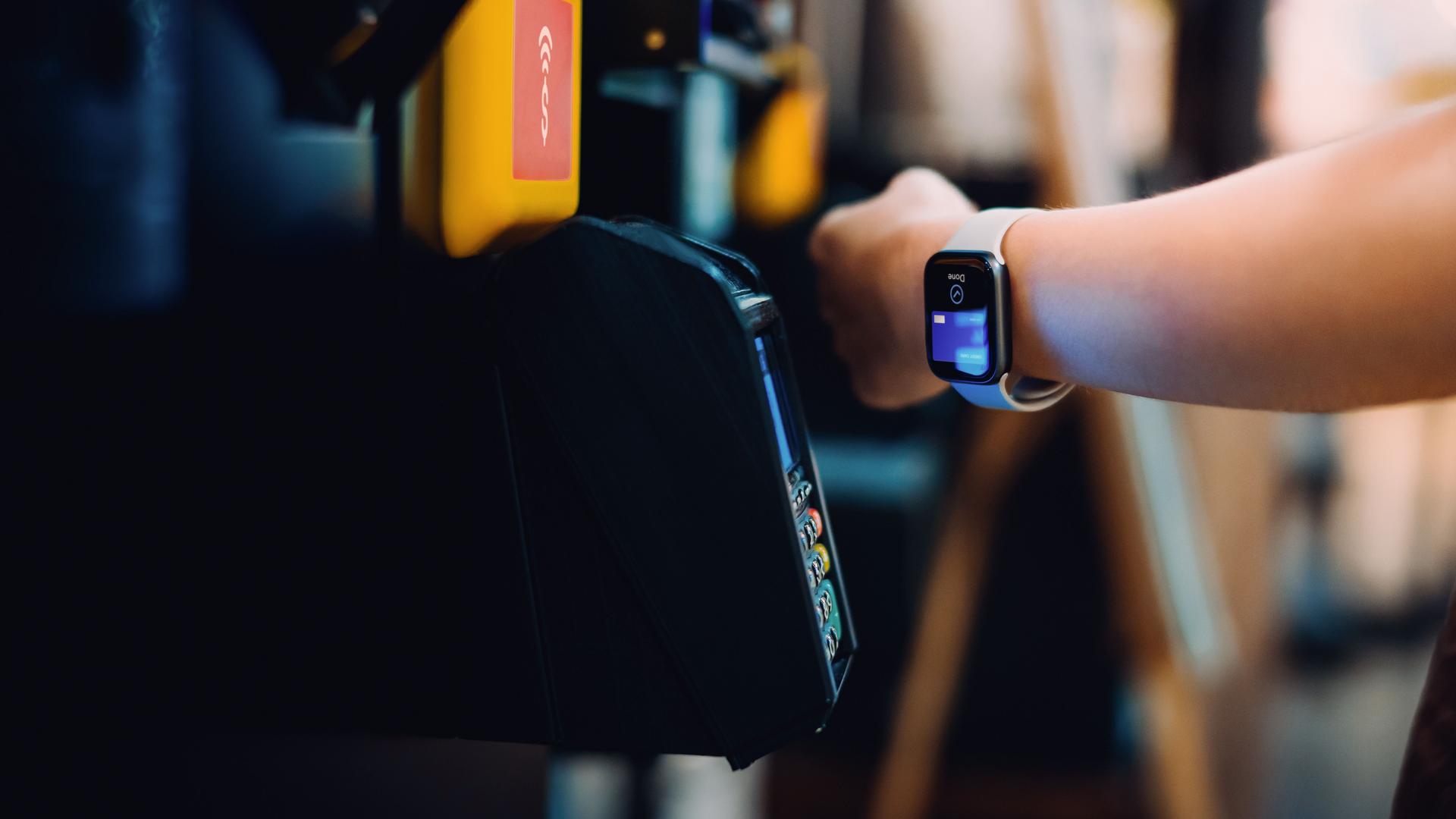 Nahaufnahme eines Handgelenks mit Smartwatch, die zum Bezahlen verwendet wird.