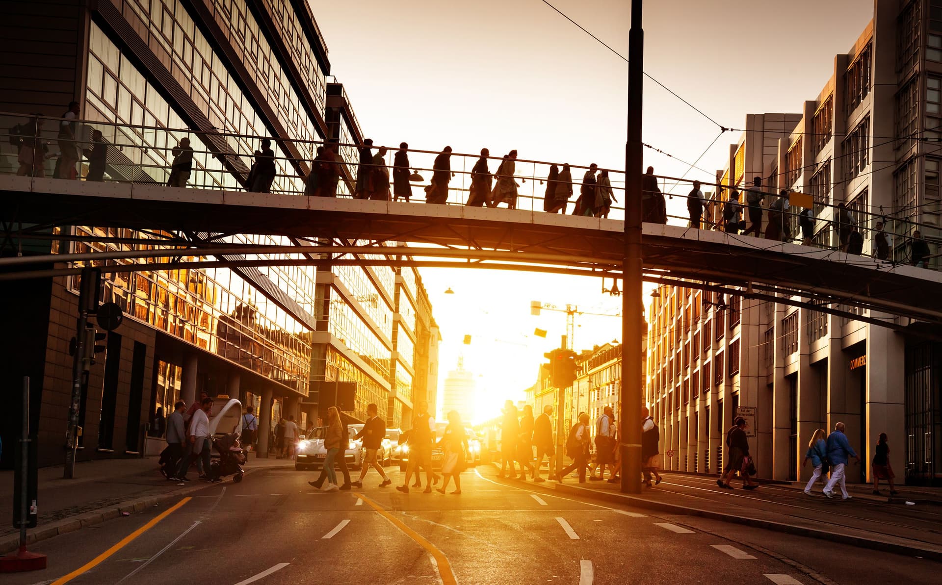 Personen gehen bei Sonnenaufgang über eine Brücke. Sie gehen zur Arbeit.