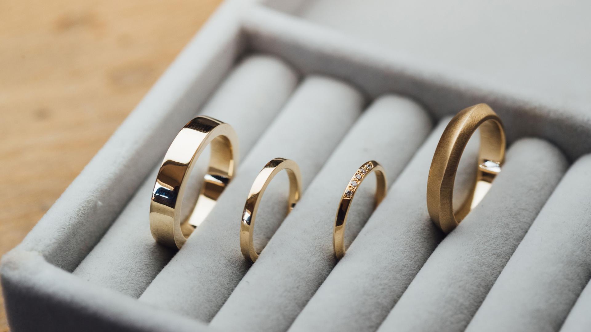 Vier goldene Ringe in einem grauen Schmuckkasten.