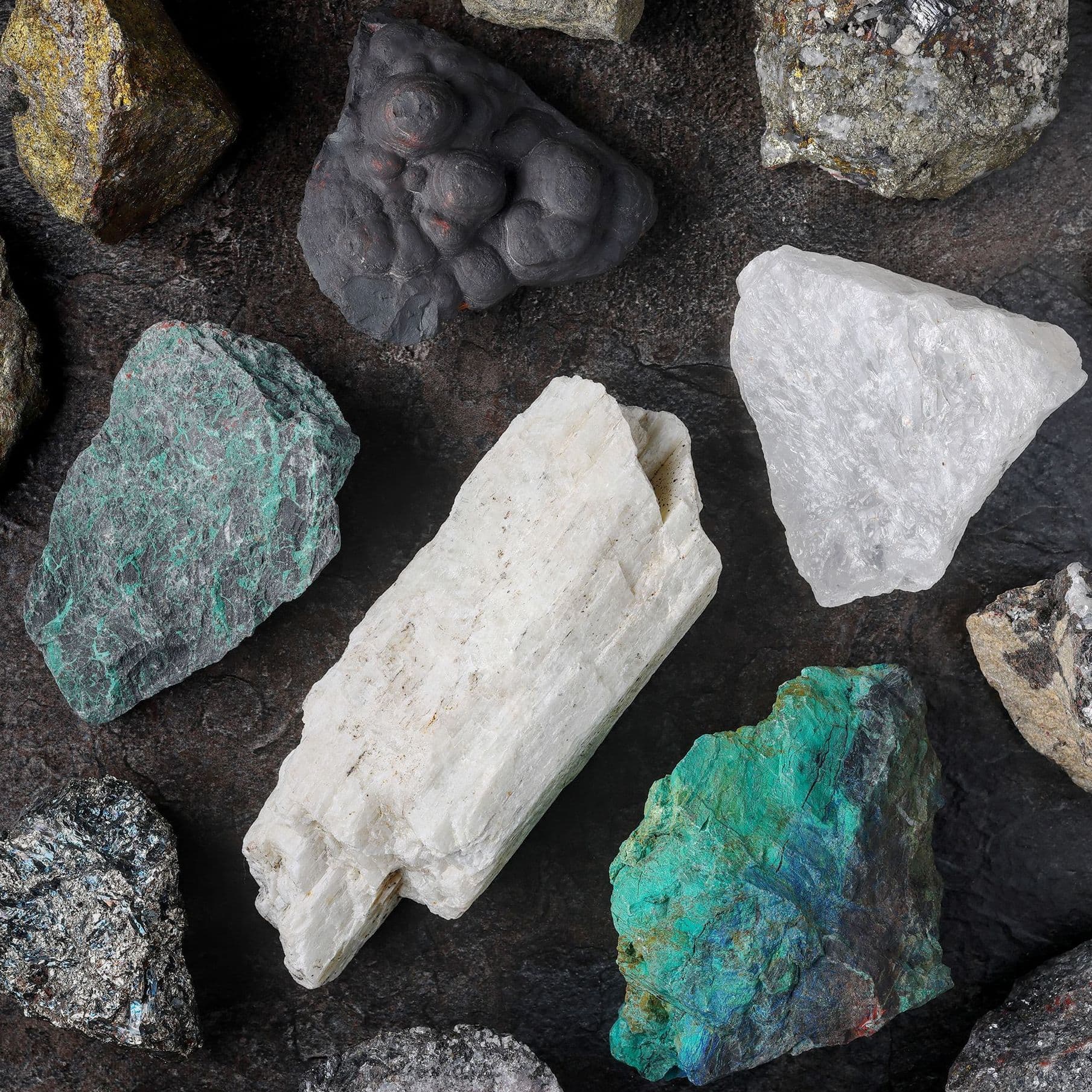 Unterschiedliche Mineralien und seltene Erden liegen auf einer Schieferplatte.
