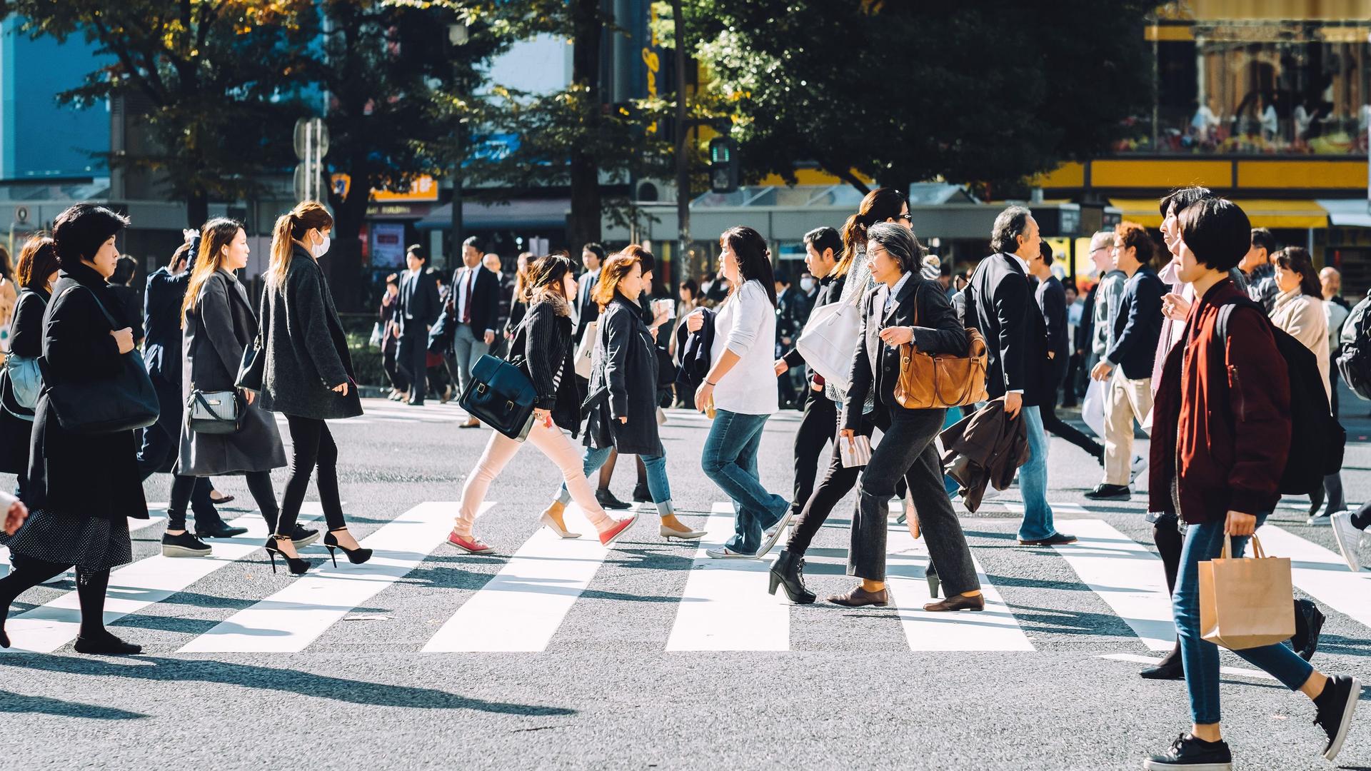 Menschenmenge, die an einem sonnigen Tag die Shibuya-Kreuzung in Tokio überqueren.