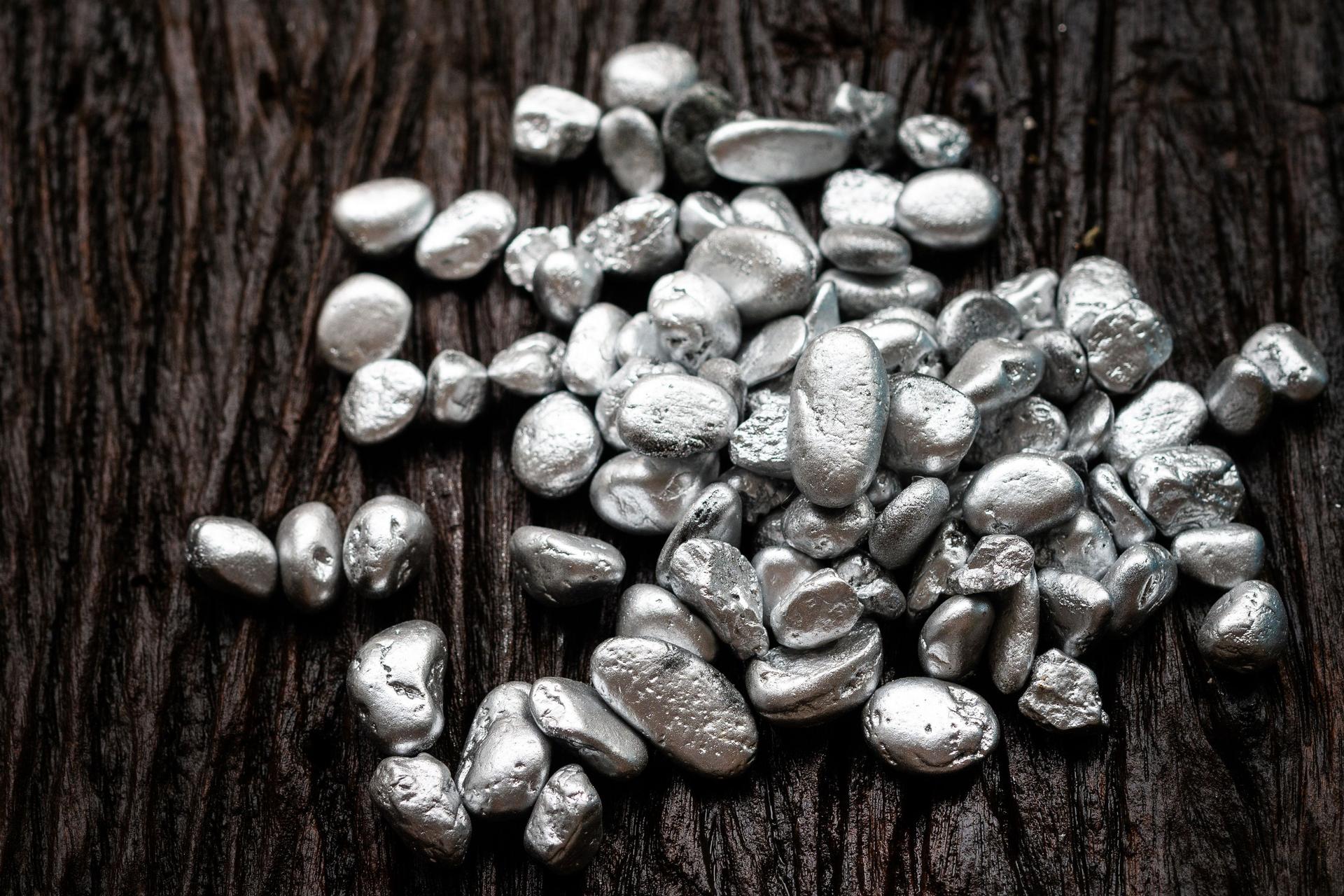 Klümpchen aus Silber- oder Platinerz auf einem Holzboden.