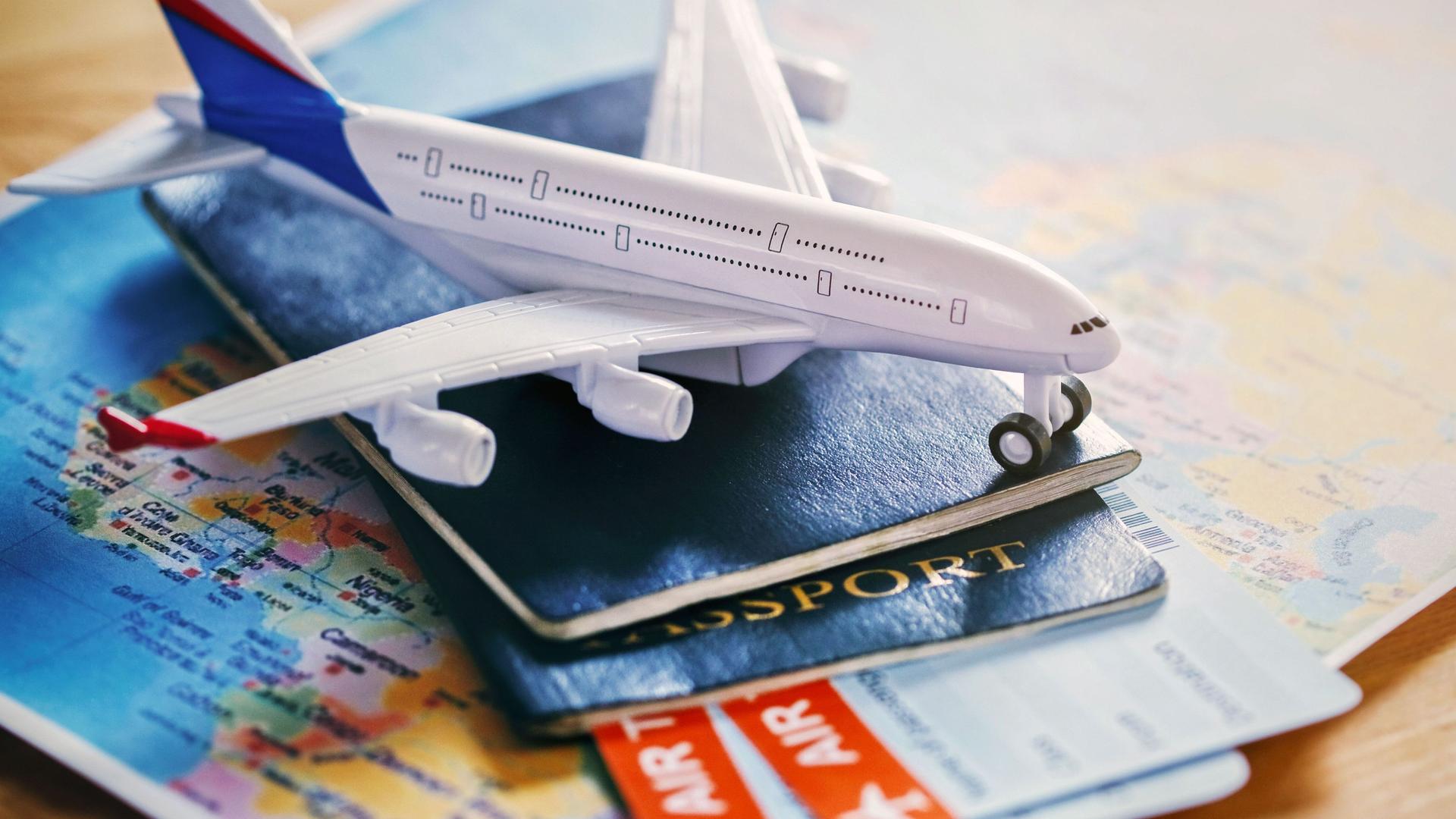 Ein Flugzeug-Modell liegt auf Reisepässen und einer Weltkarte.