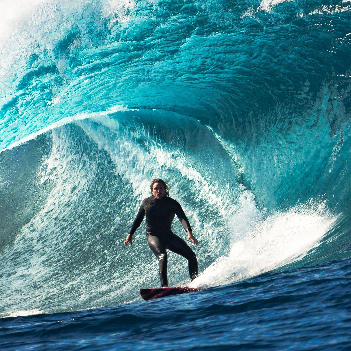 Mann auf einem Surfboard inmitten einer Welle.