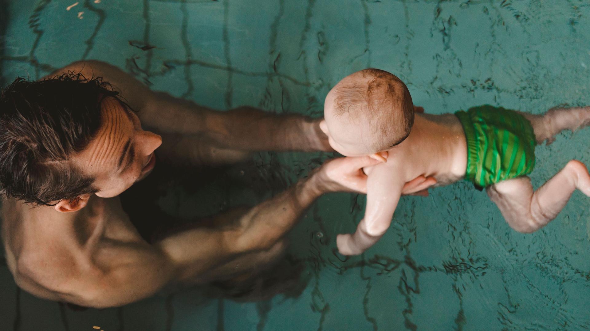 Junger Vater mit Baby in einem Schwimmbecken