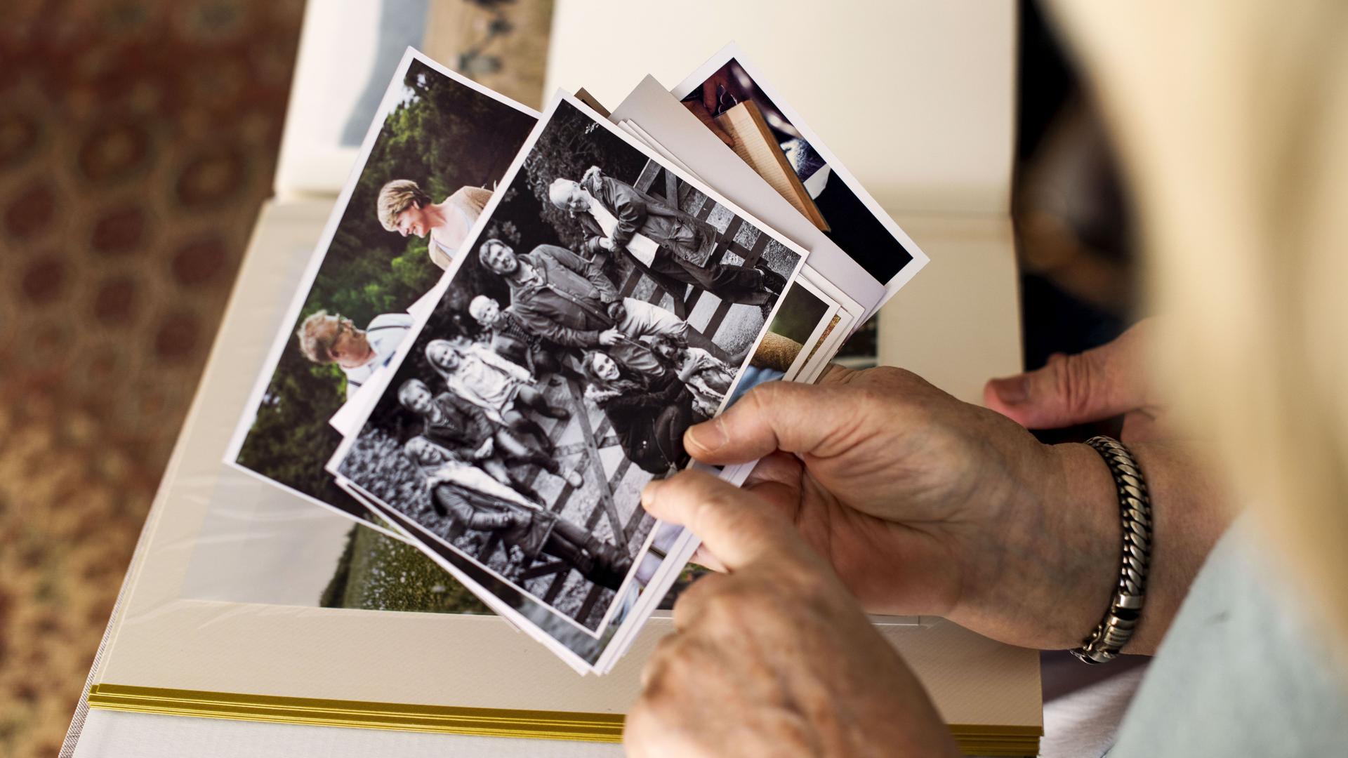 Draufsicht auf alte Fotos in der Hand einer Seniorin. 
