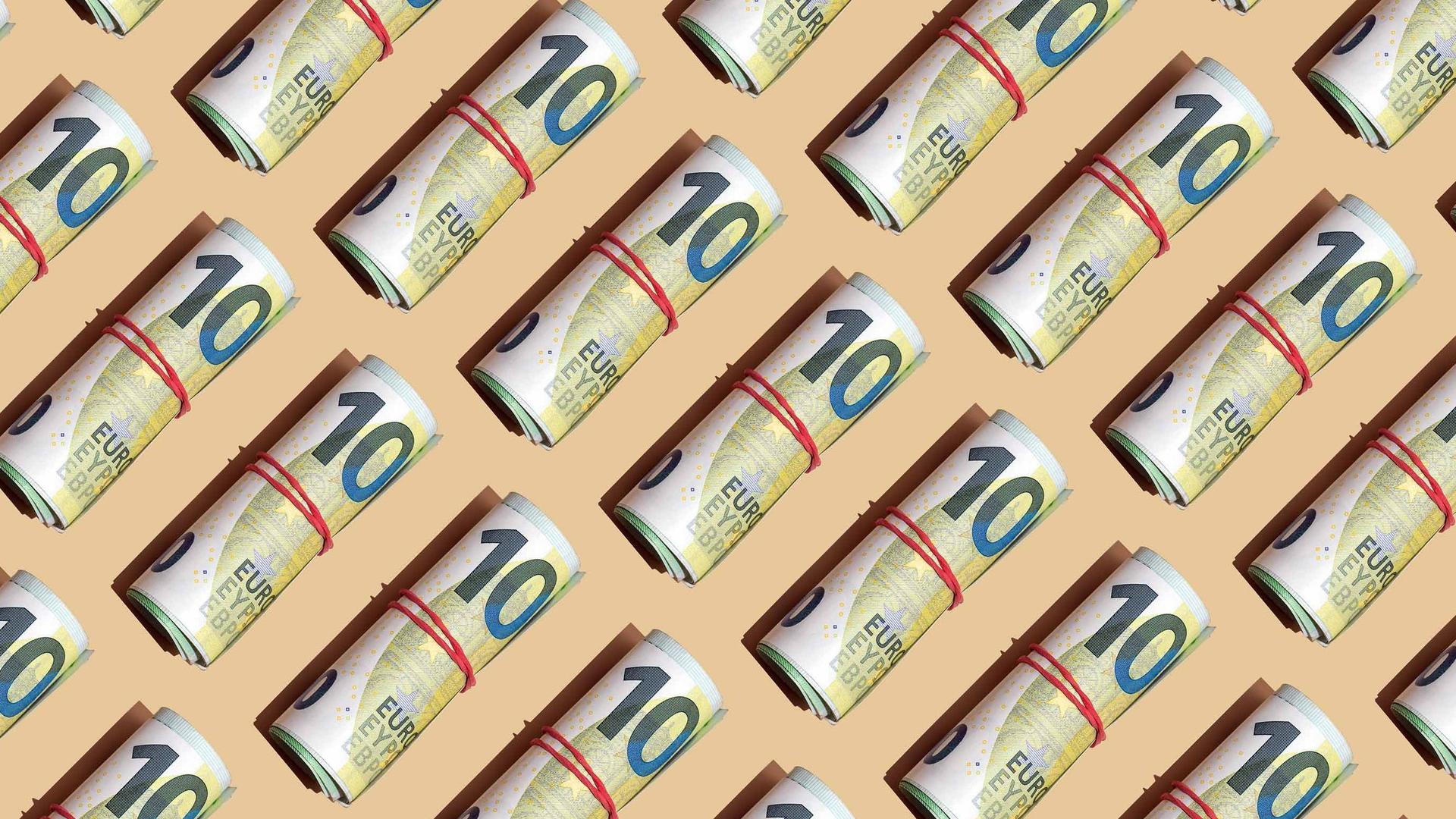 Ein grafisches Bild mit vielen 100 Euro Banknoten mit roten Gummibändern zu Geldbündeln zusammengerollt. Sie liegen aneinandergereiht mit gleichen Abständen auf einem gelben Untergrund.