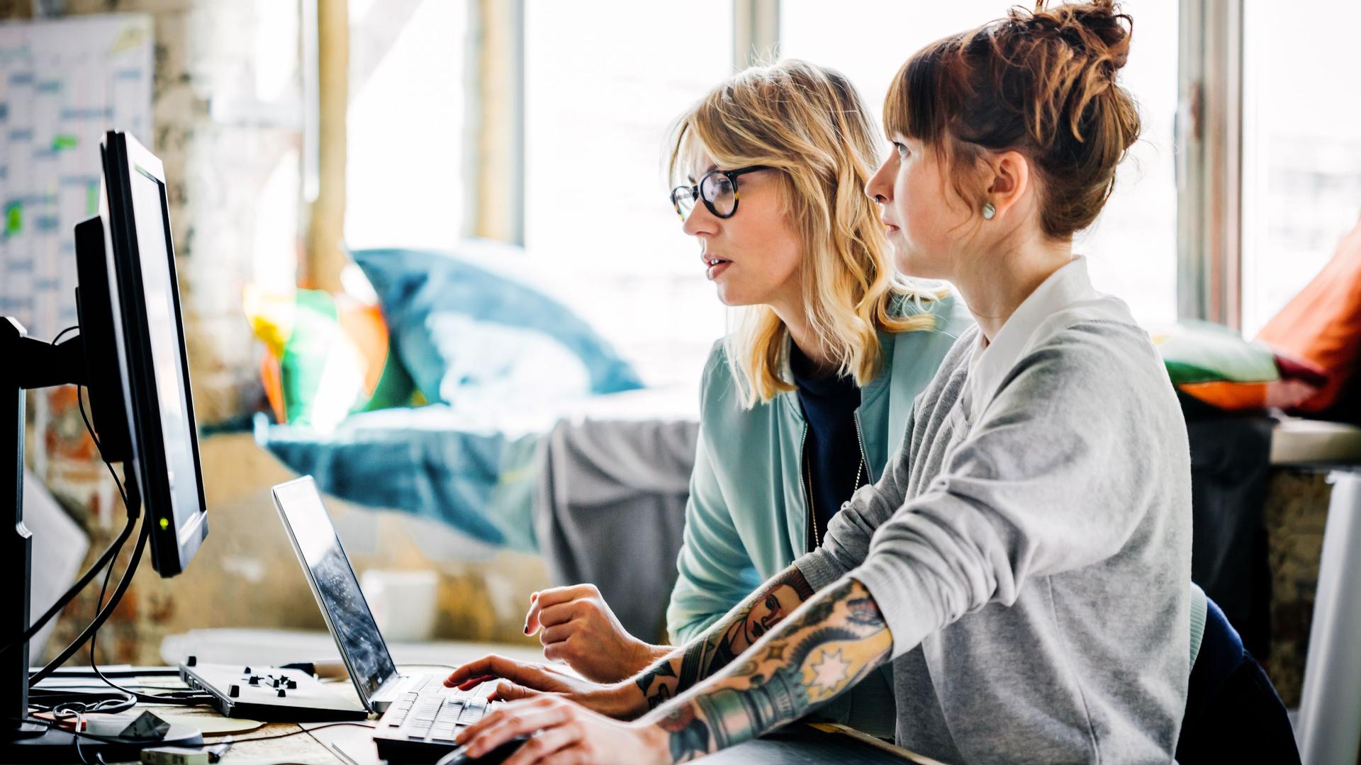 Zwei junge Frauen, die zusammen an einem Computer arbeiten.