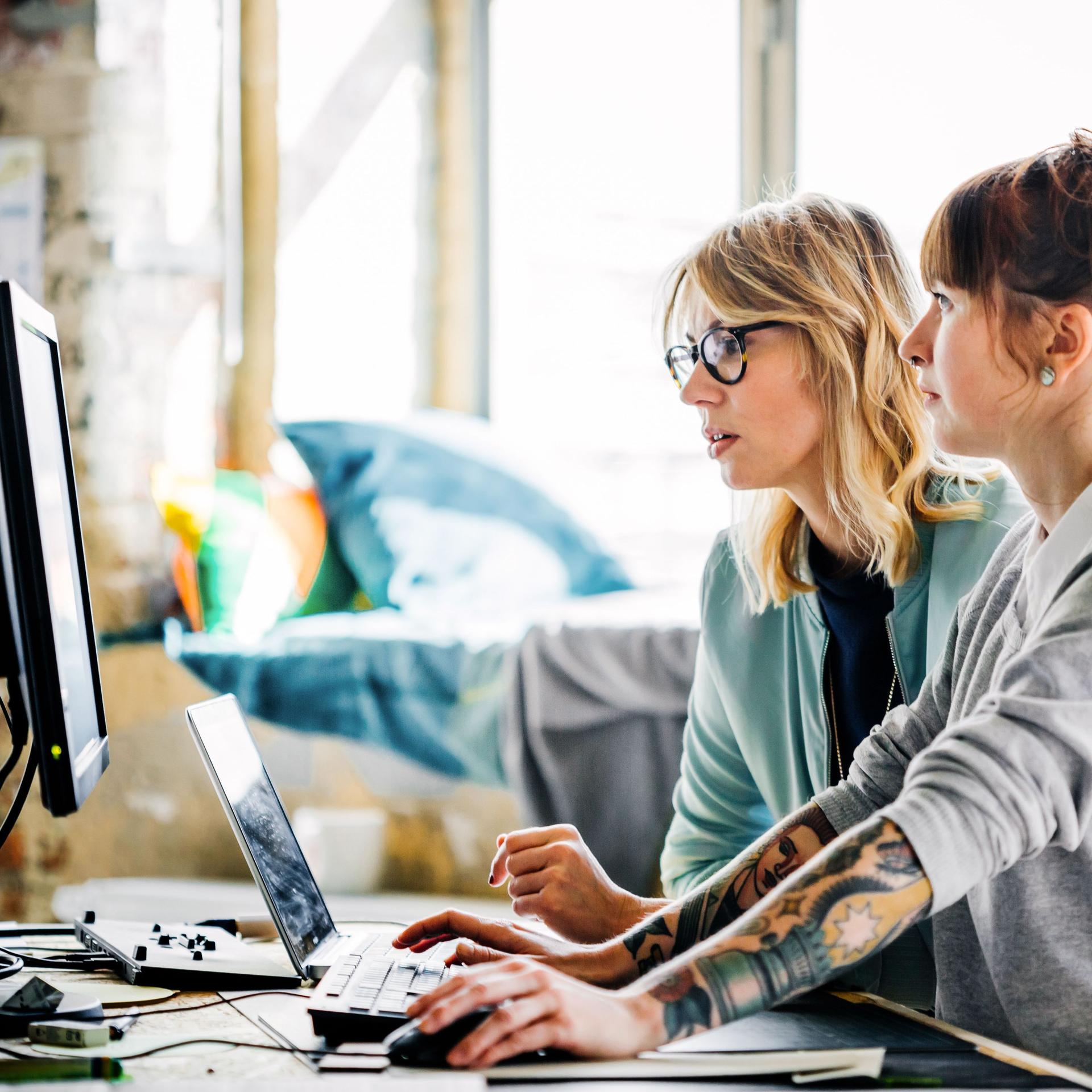 Zwei junge Frauen, die zusammen an einem Computer arbeiten.