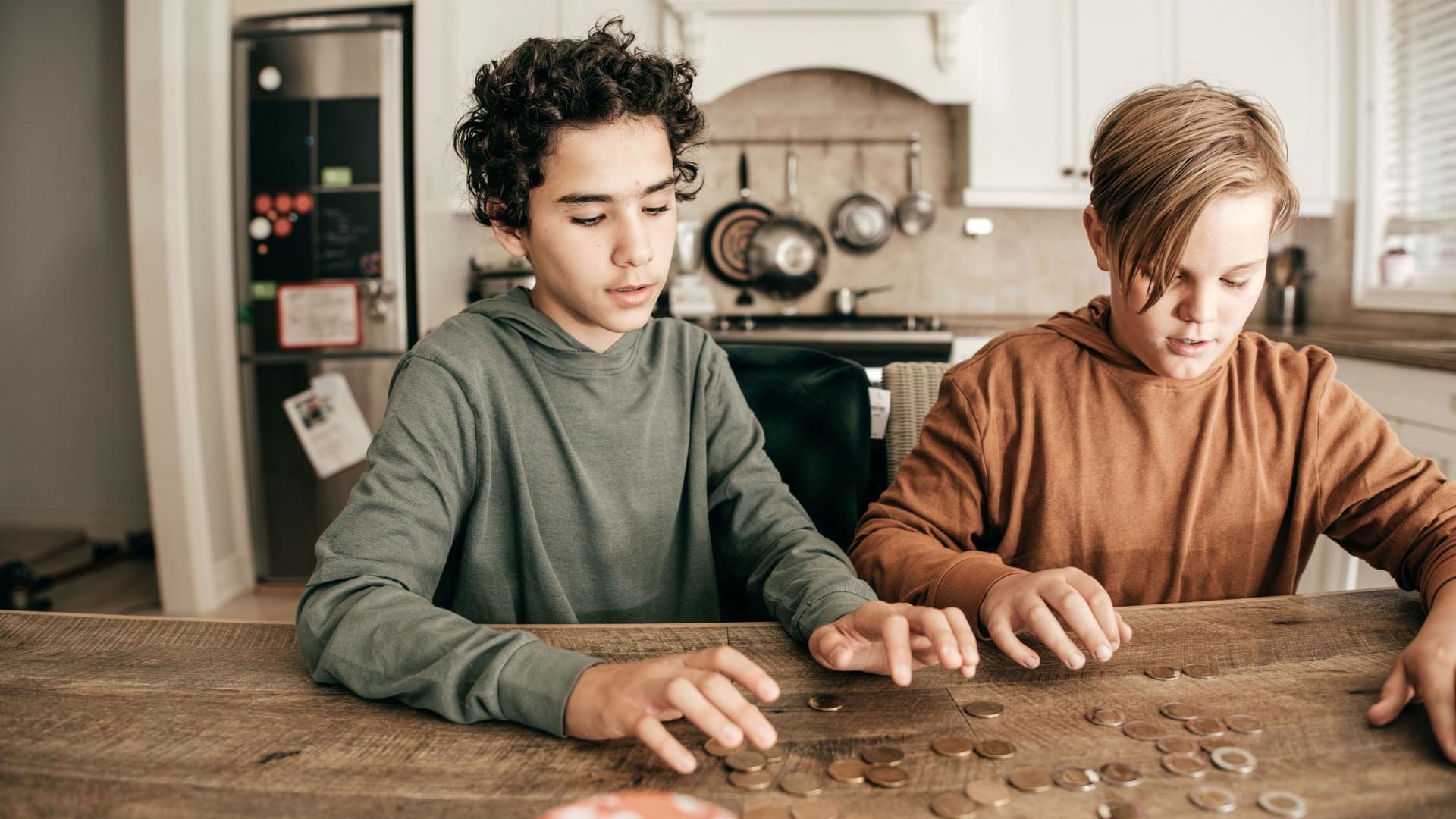Zwei Jungs sitzen in der Küche und sortieren Münzen.