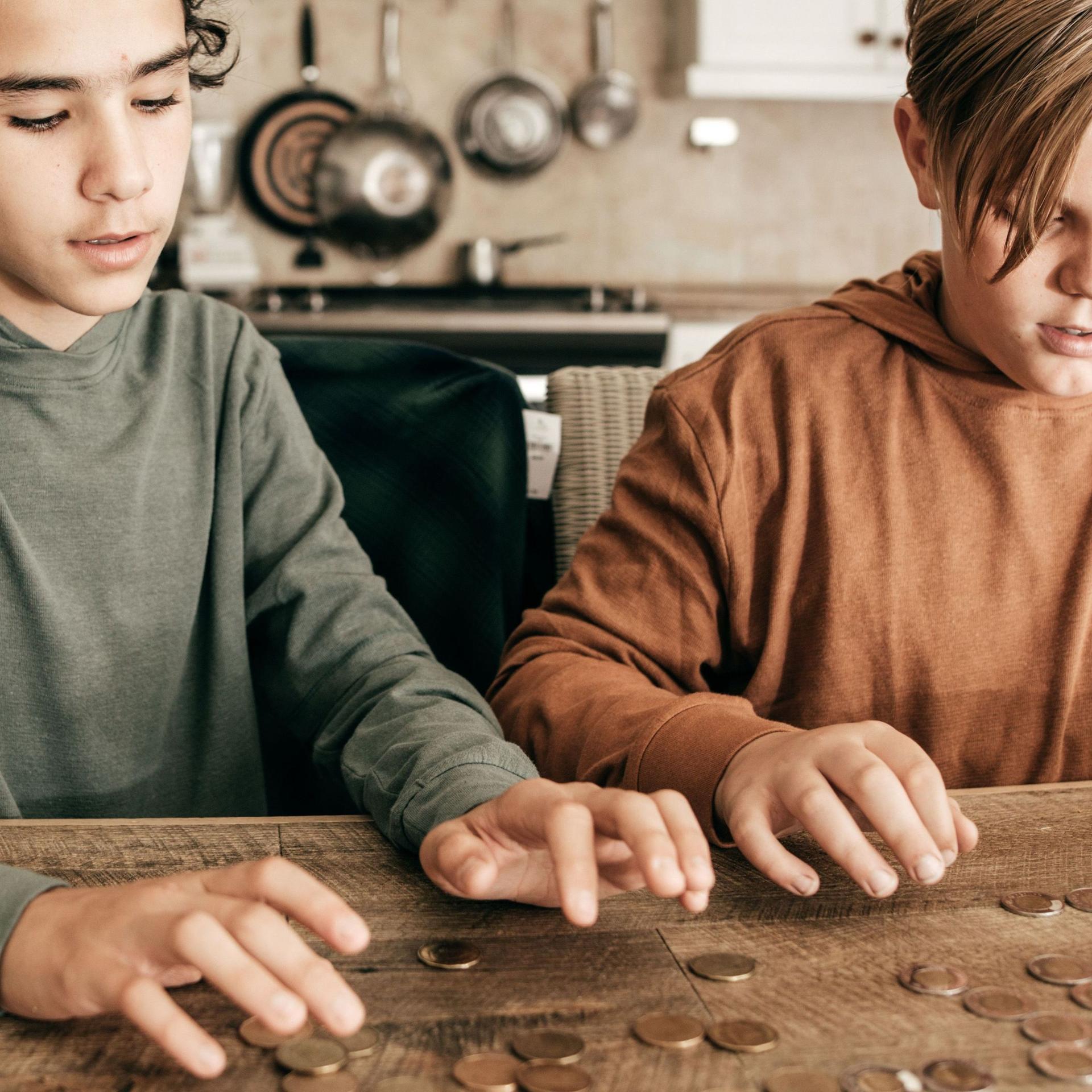 Zwei Jungs sitzen in der Küche und sortieren Münzen.