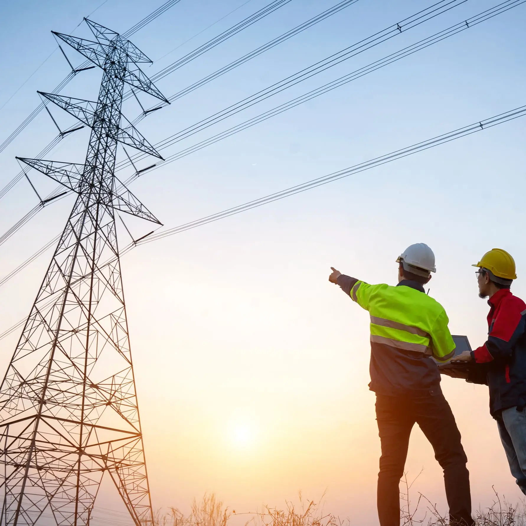 Zwei Männer mit Helmen stehen draußen und einer zeigt auf einen Strommast