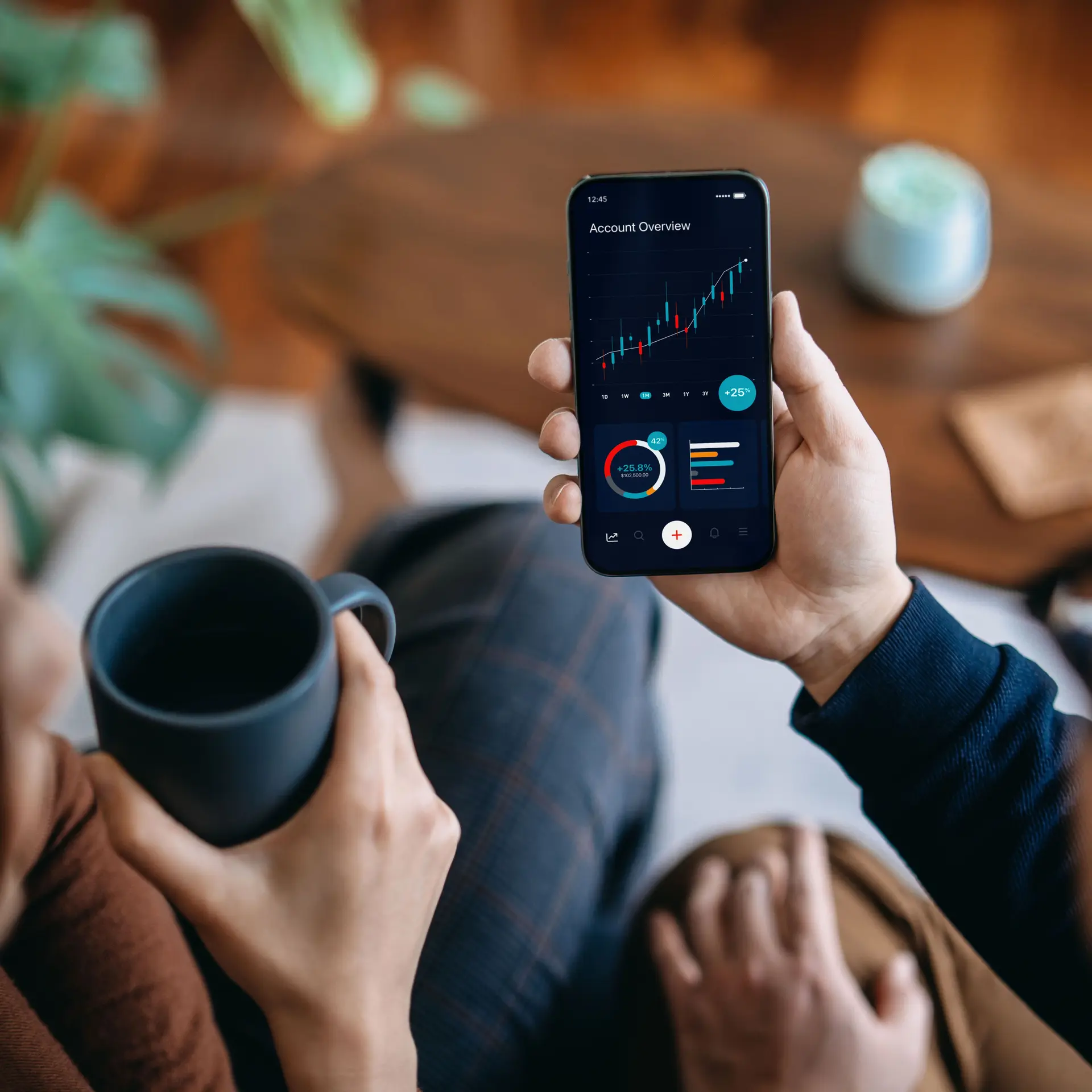 Zwei Personen trinken Kaffee und schauen auf die Börsenentwicklung am Handy.