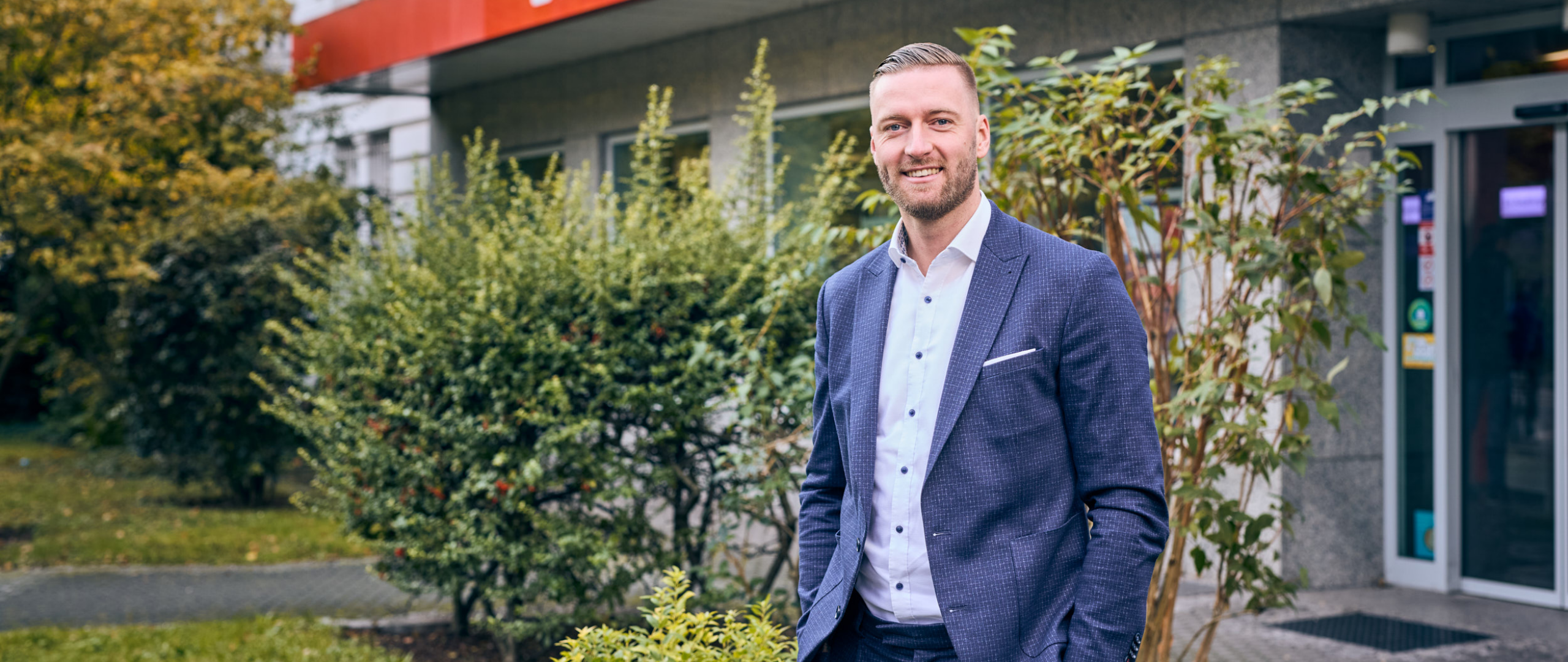 Bankberater steht vor einer Filiale der Frankfurter Sparkasse