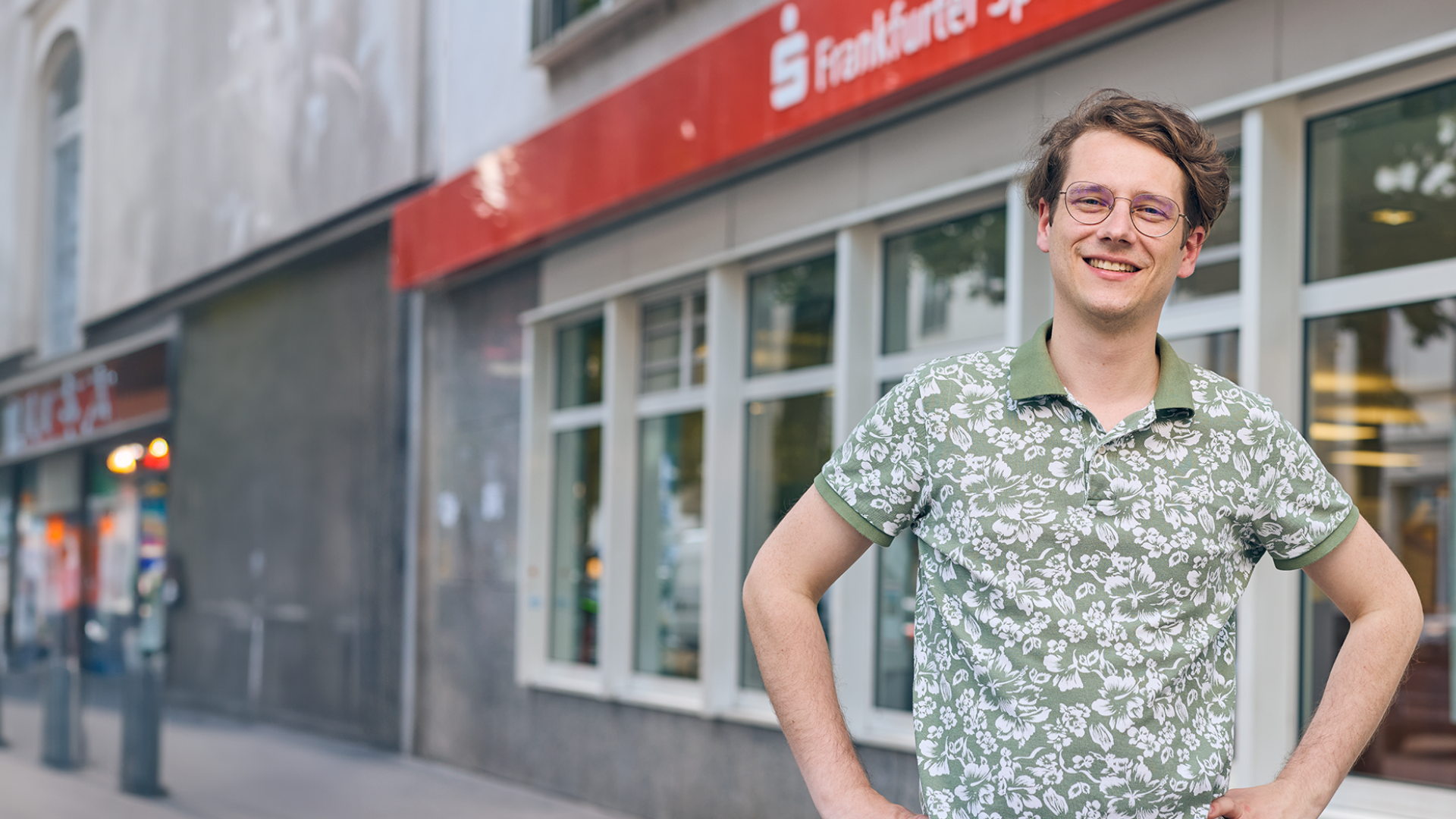 Dualer Student steht vor einer Filiale der Frankfurter Sparkasse