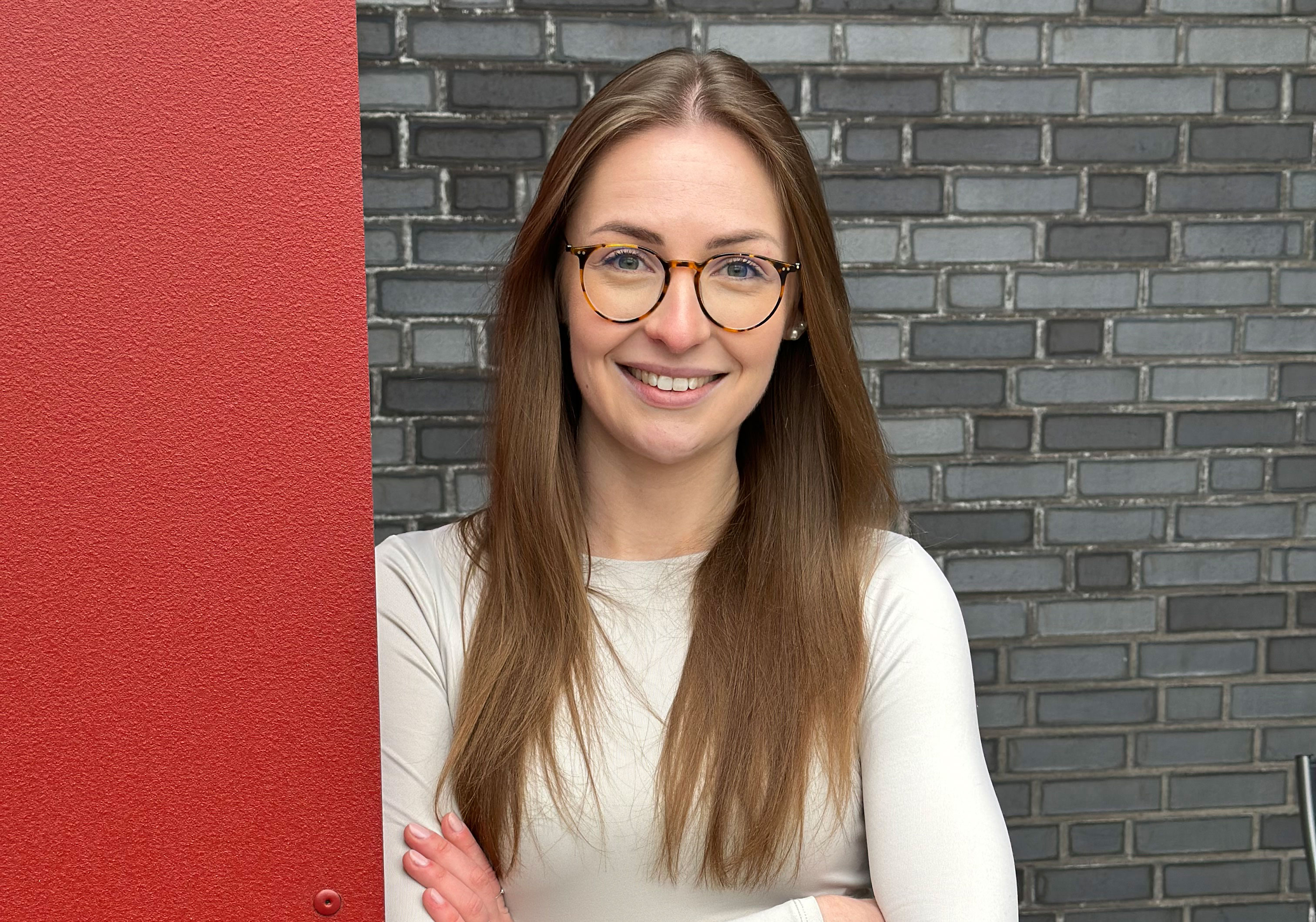 Ausbildungsleiterin Deike Lehmann lehnt an einer roten Wand.