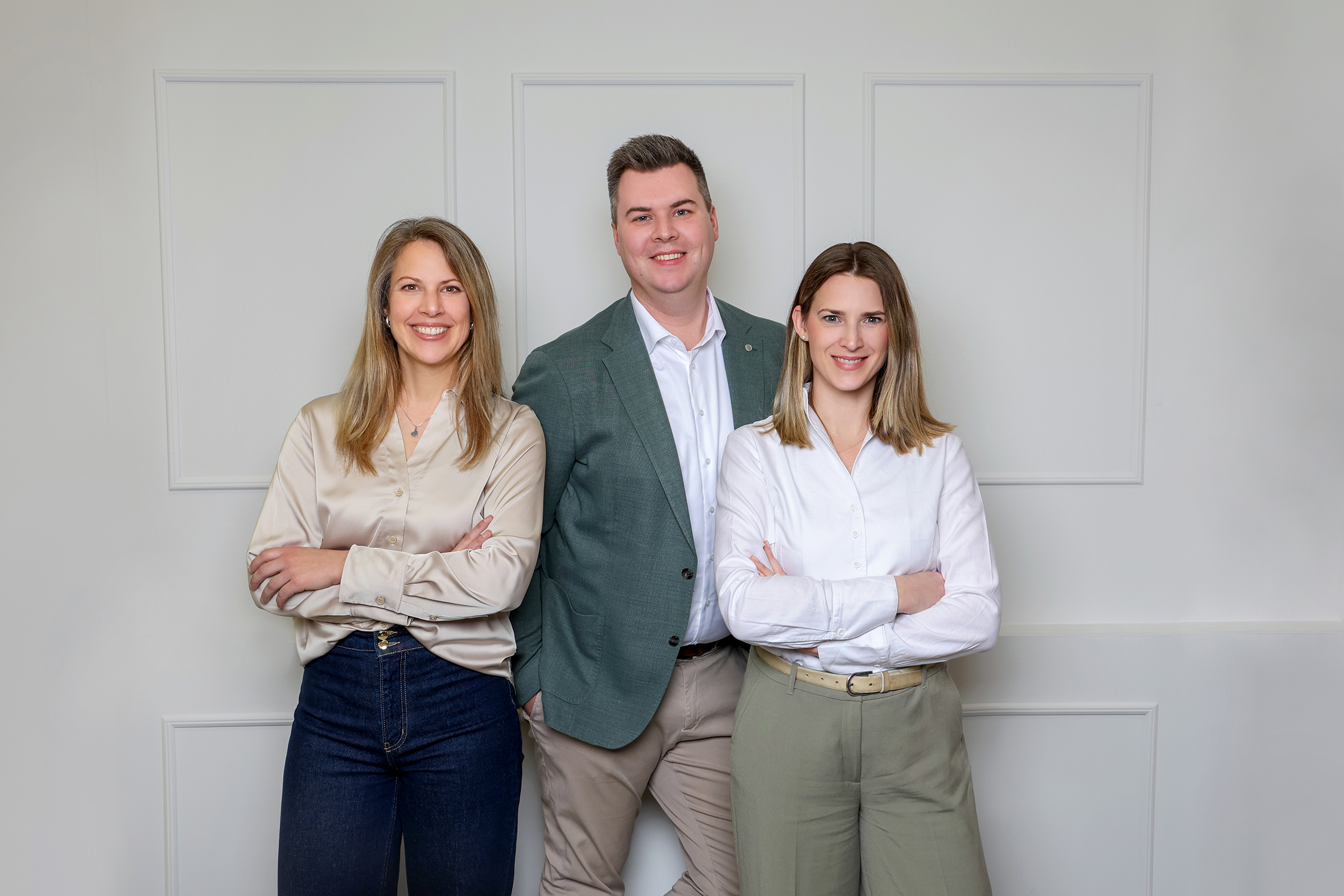 Team steht vor einer Wand - zwei Frauen und ein Mann 