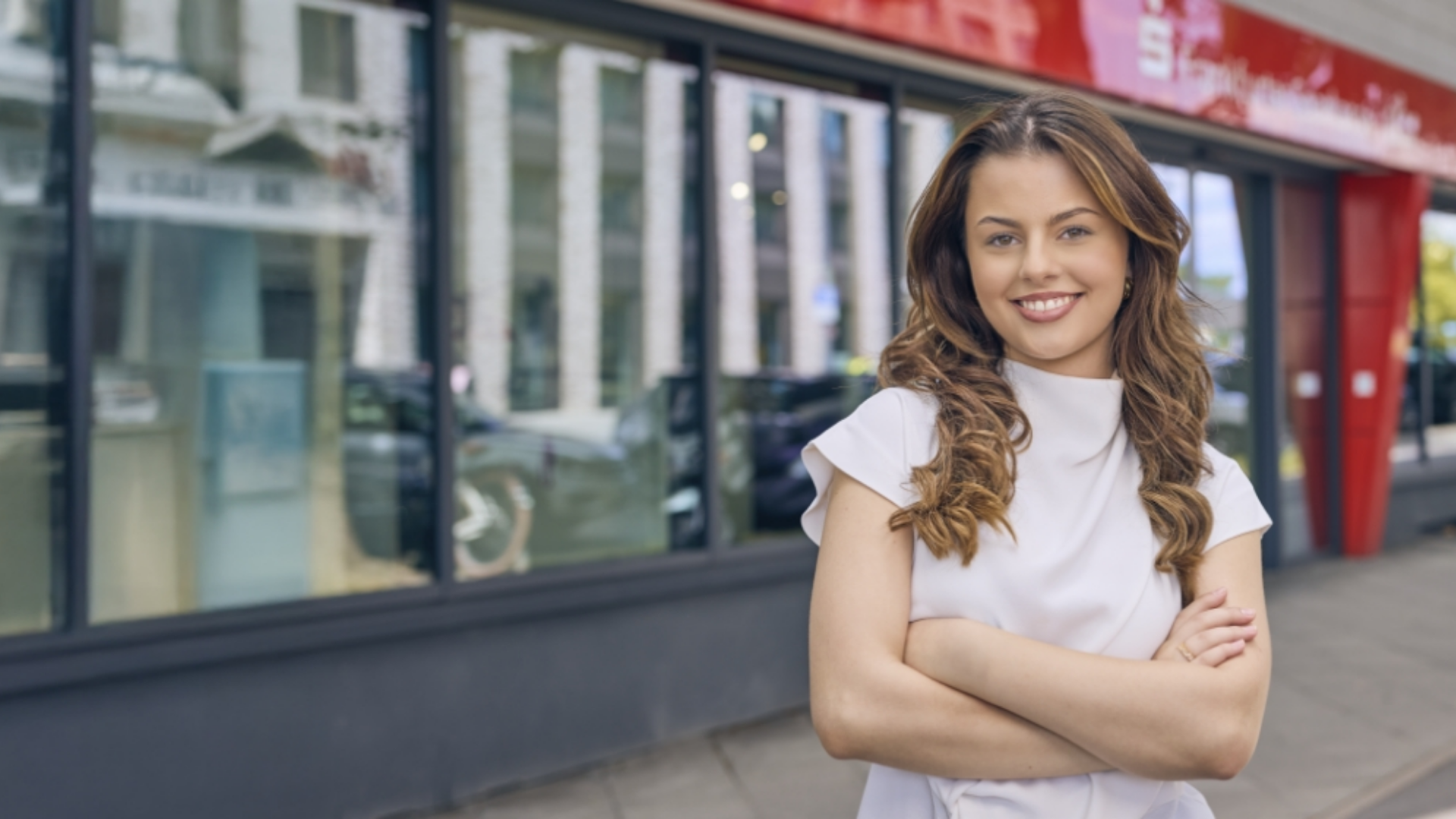 Auszubildende steht vor einer Filiale der Frankfurter Sparkasse