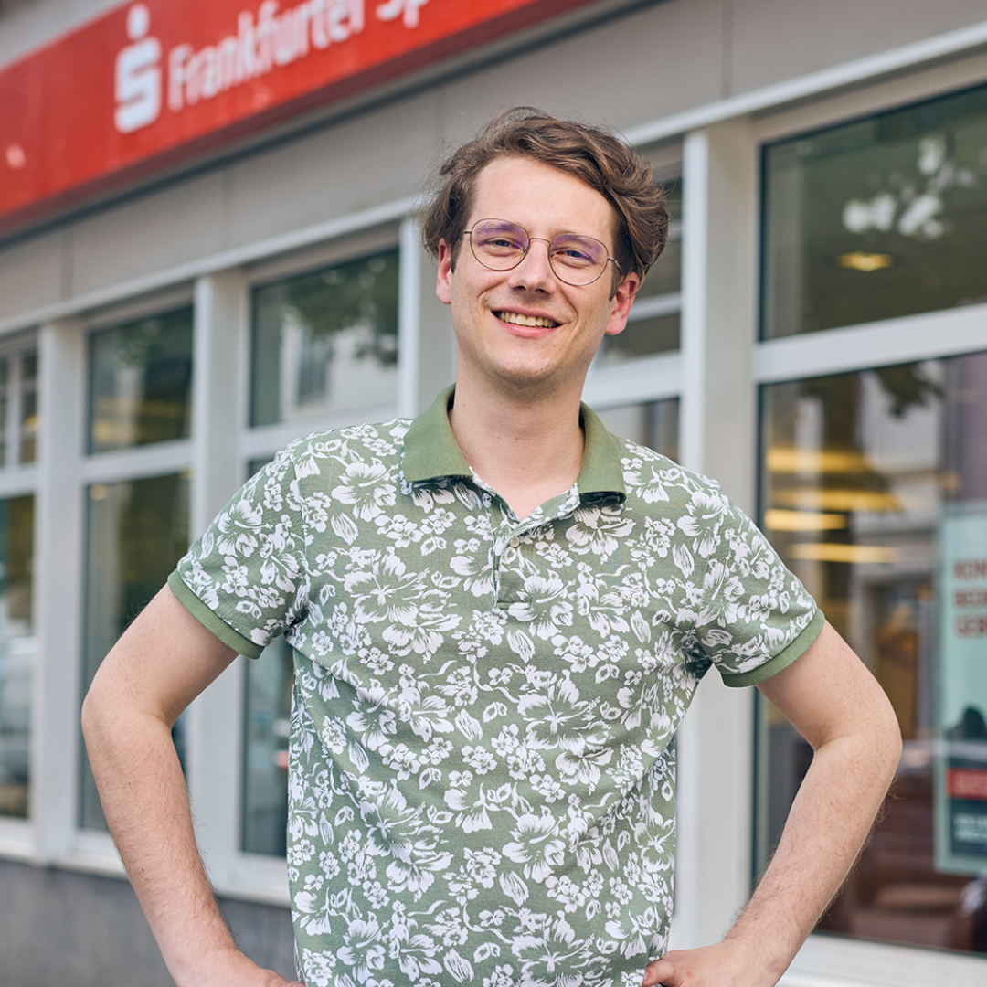 Dualer Student steht vor einer Filiale der Frankfurter Sparkasse