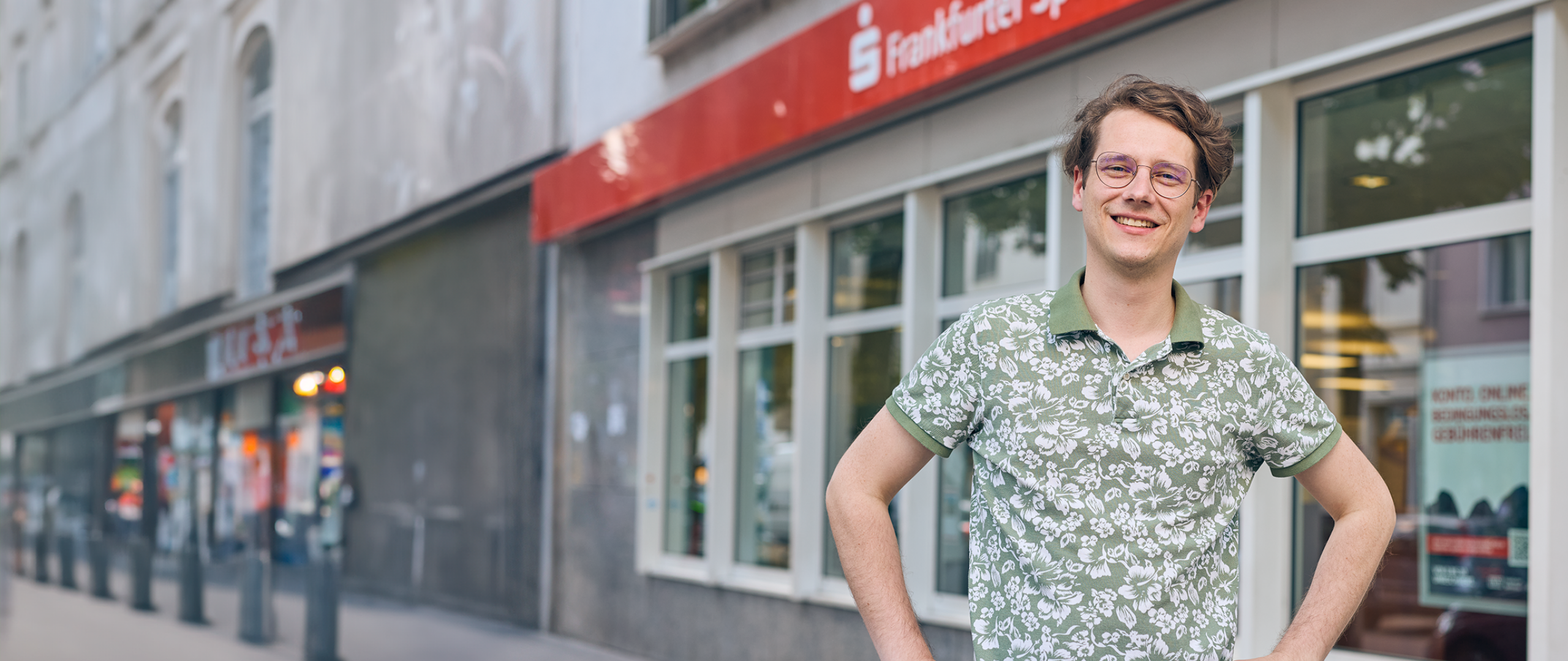 Dualer Student steht vor einer Filiale der Frankfurter Sparkasse

