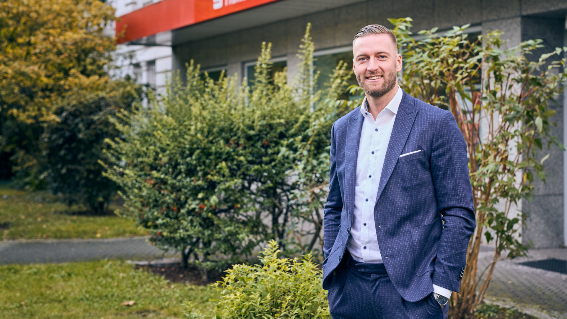 Bankberater steht vor einer Filiale der Frankfurter Sparkasse
